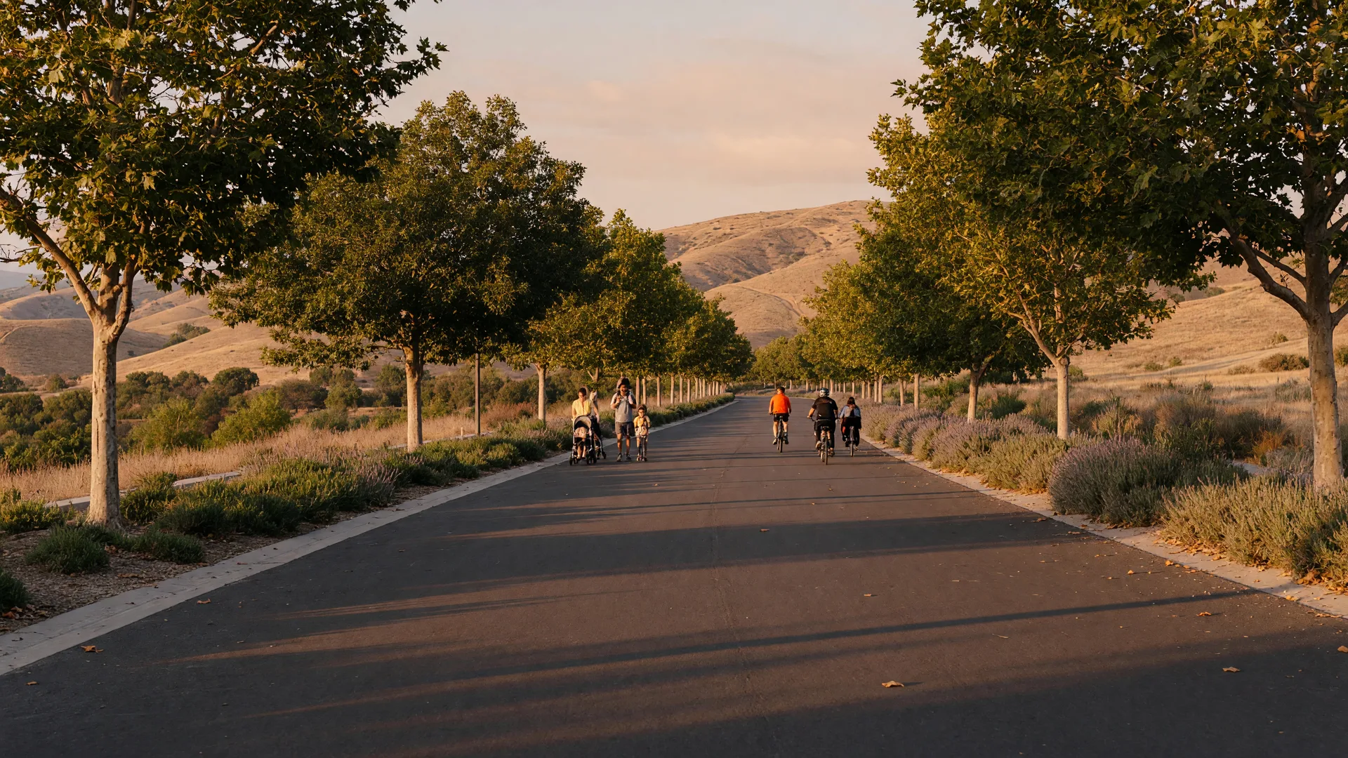 A flat, tree-lined paved paseo trail in Santa Clarita Valley with dappled shade and distant cyclists