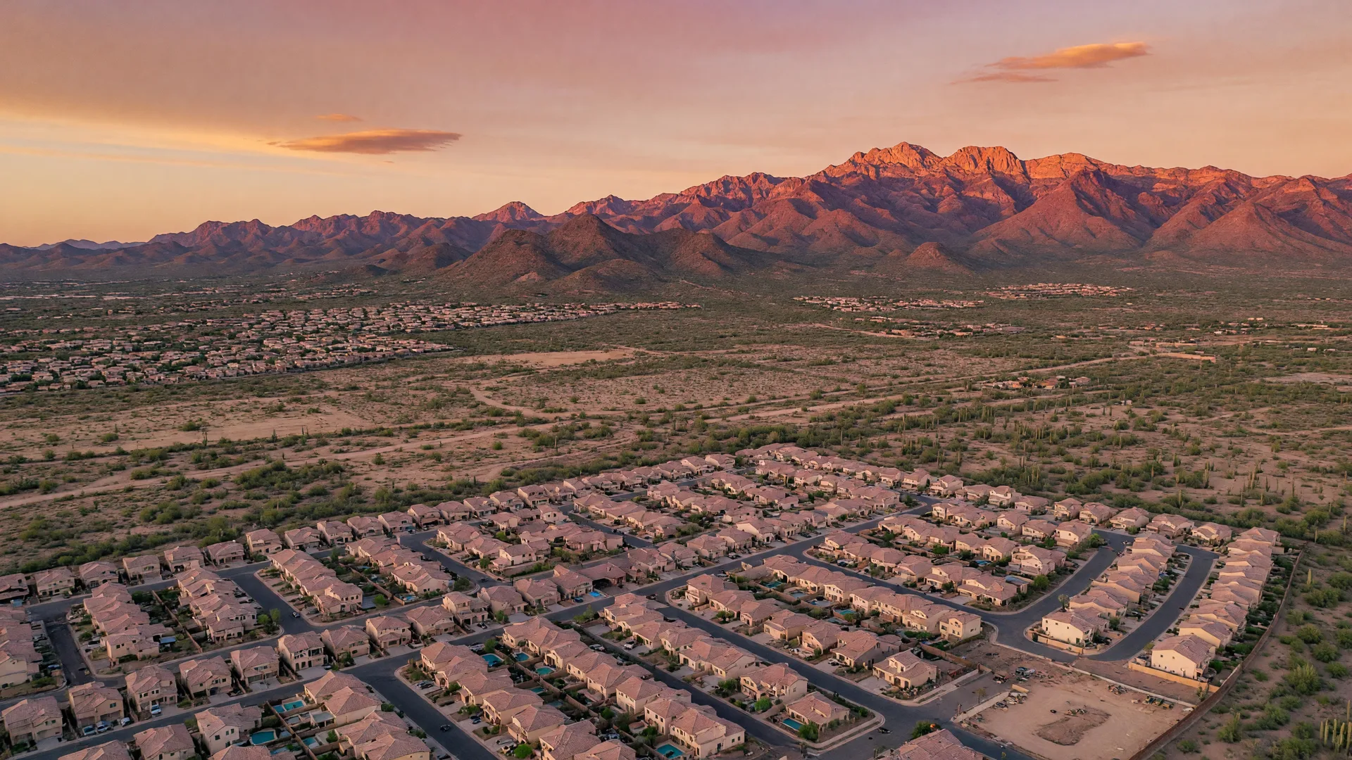 Golden hour aerial view of Buckeye, Arizona, with master-planned communities spread across the desert and the White Tank Mountains on the horizon