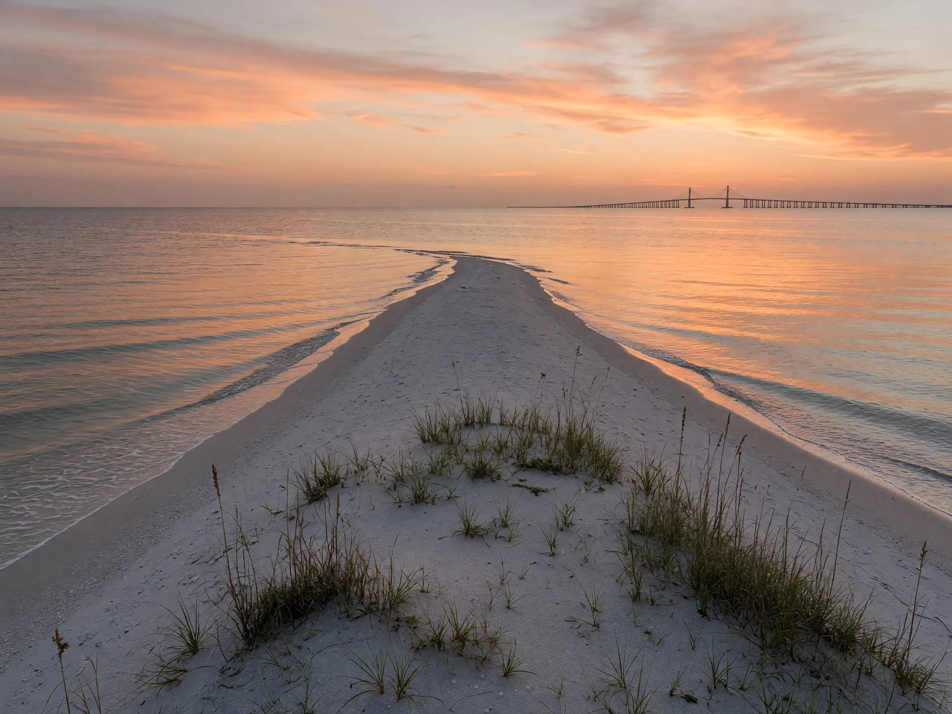 Sunrise at Bean Point at the northern tip of Anna Maria Island, where the Gulf of Mexico meets Tampa Bay, with sea oats in the foreground and the Sunshine Skyway Bridge on the horizon