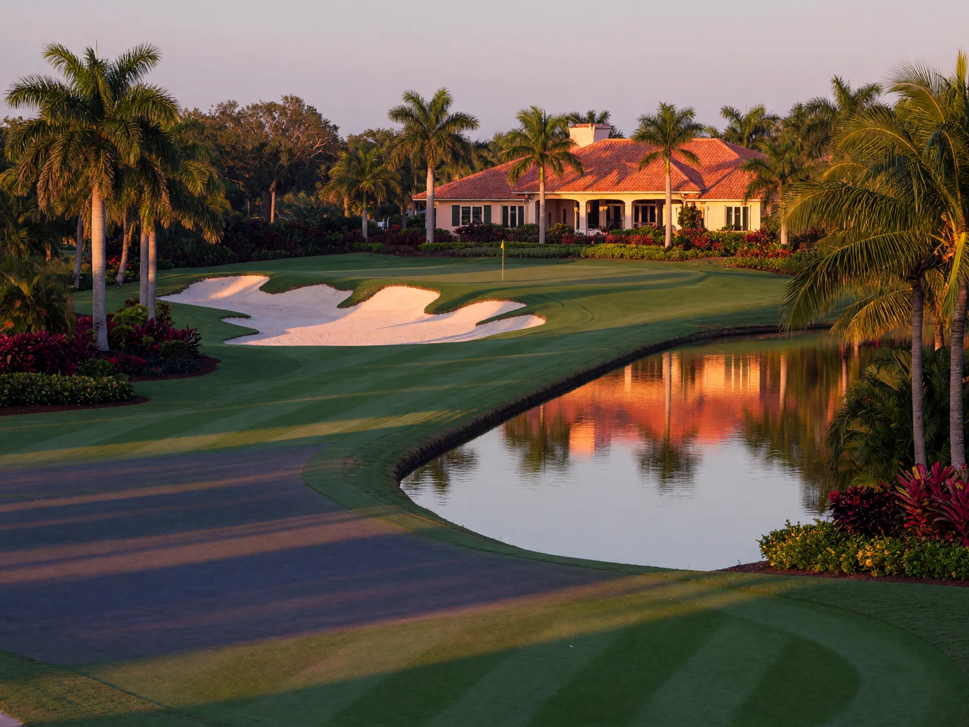A championship golf fairway with palms and a water hazard at golden hour in Southwest Florida