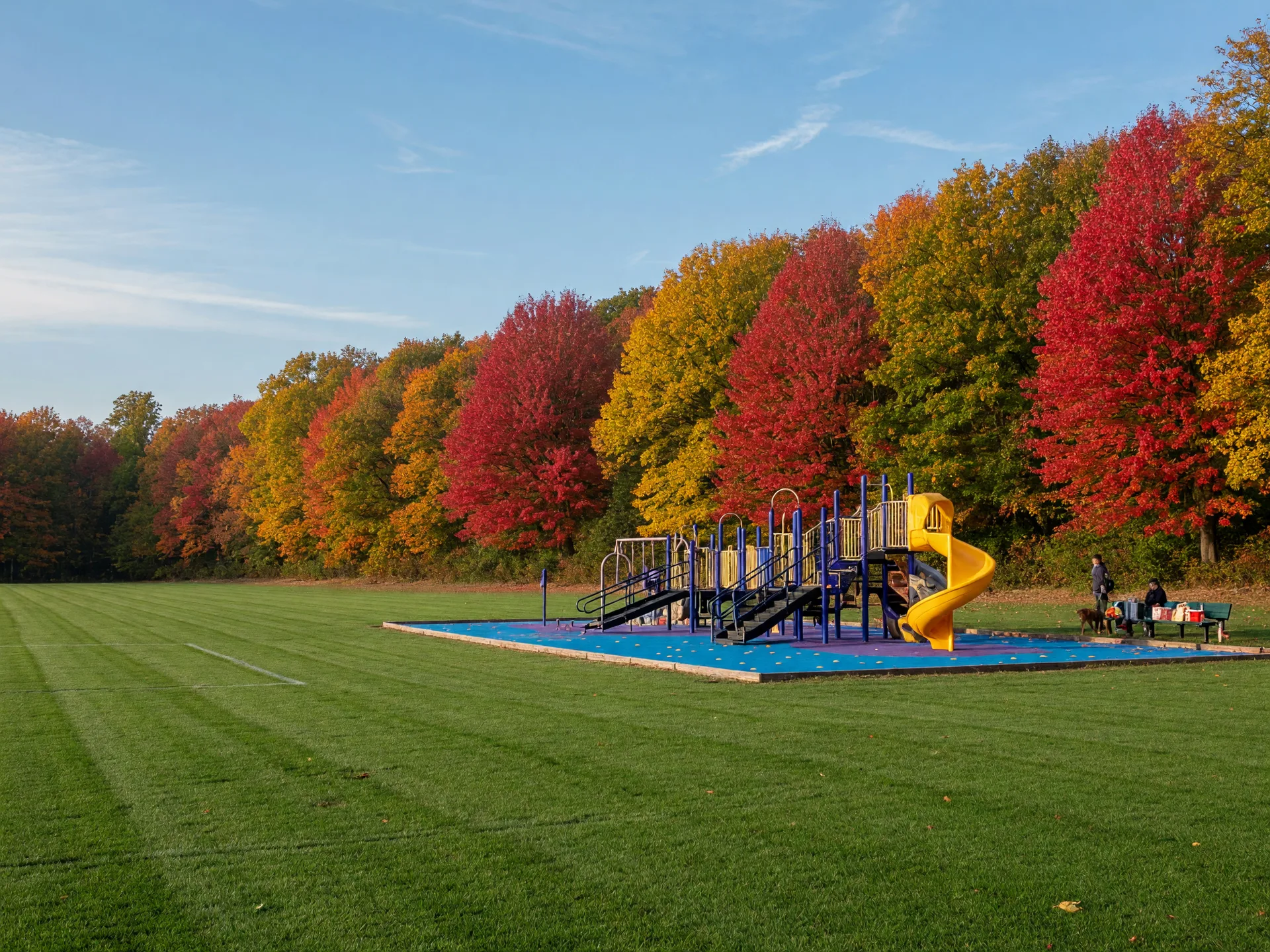 Delran Community Park on a bright fall morning, with an athletic field, accessible playground, and autumn trees