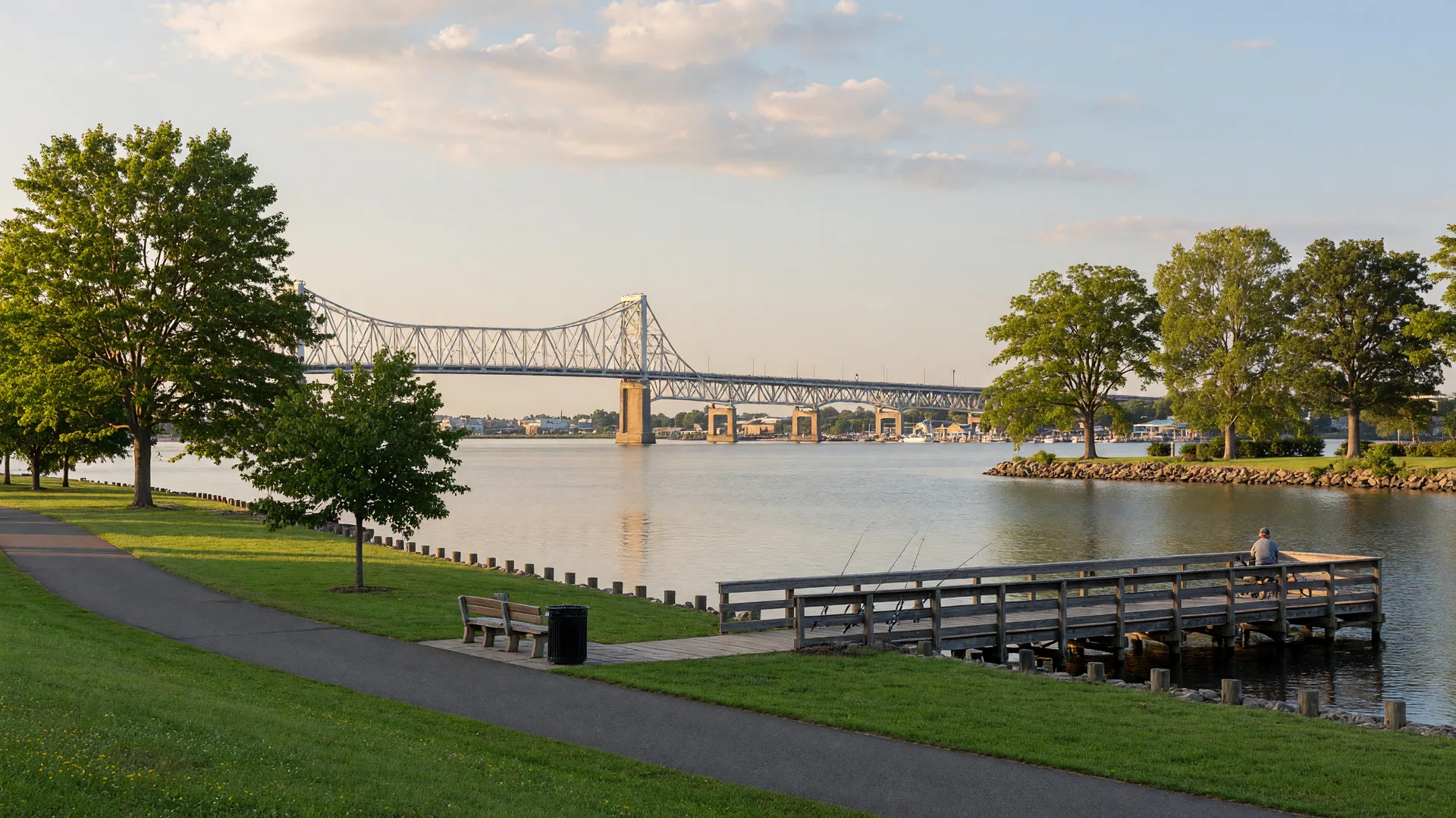 Florence NJ Delaware River waterfront with wooden fishing pier, walking paths, and the Burlington-Bristol Bridge in the distance on a warm summer morning