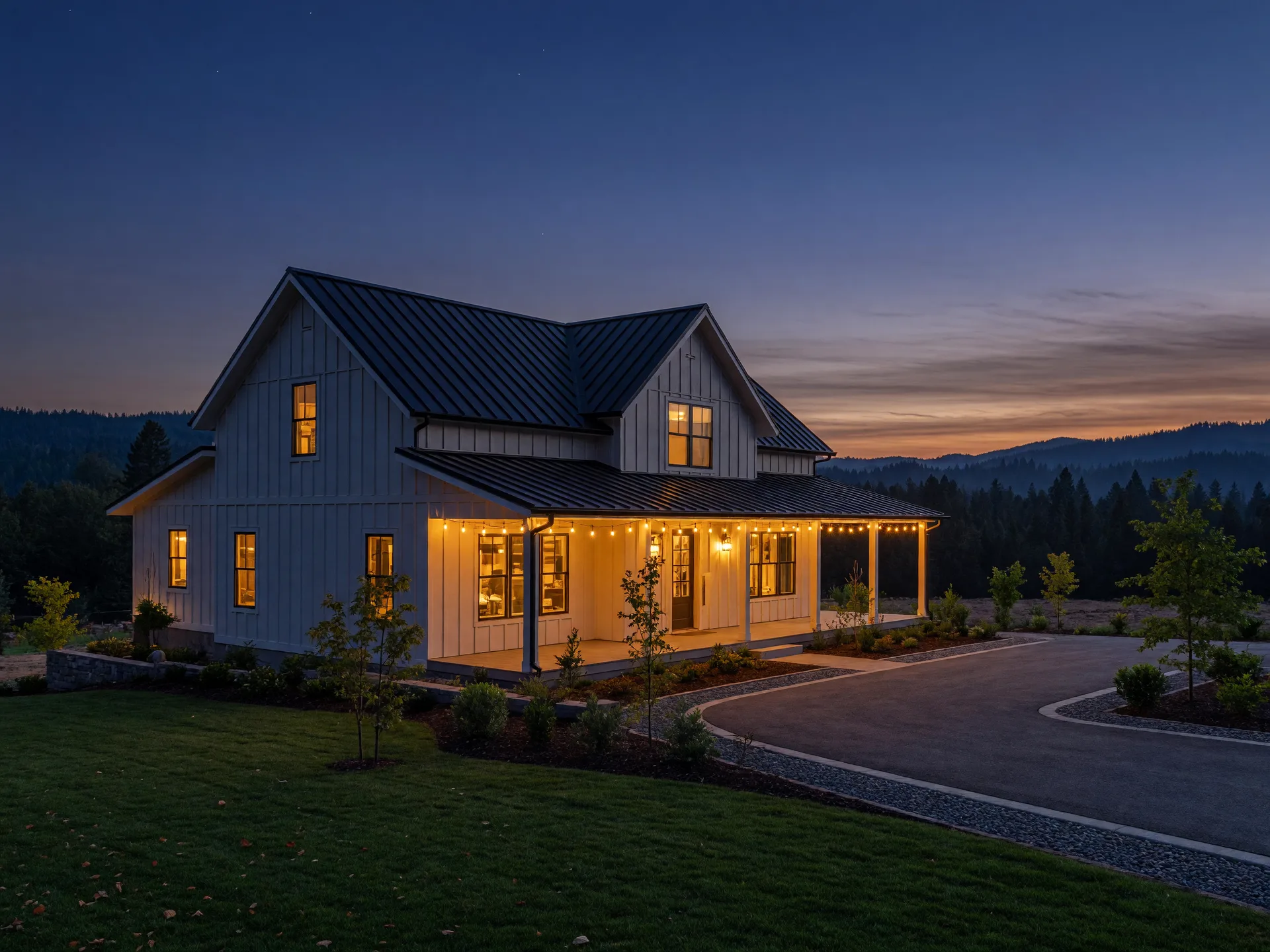 Modern farmhouse at twilight with warm light glowing from its windows in Southern Oregon