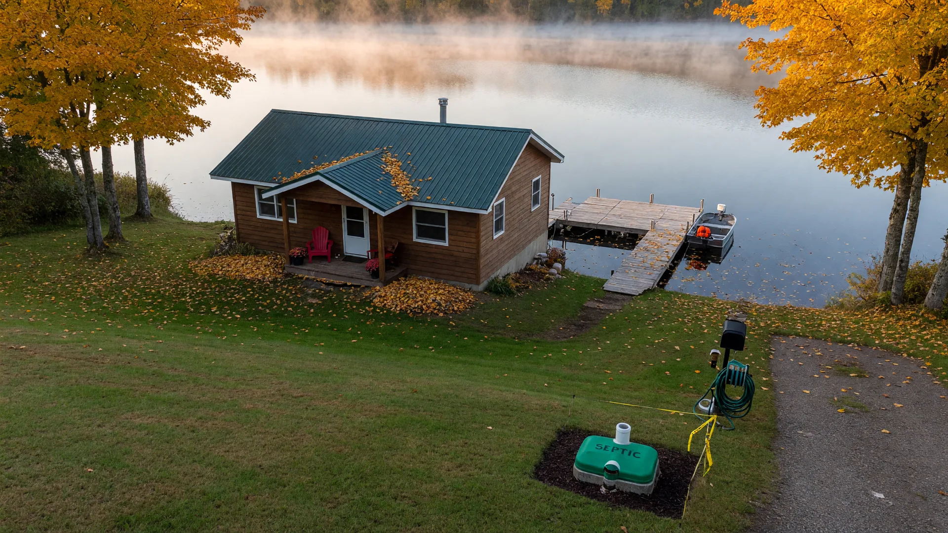Minnesota lake cabin on a grassy slope in fall with a marked septic access in the yard
