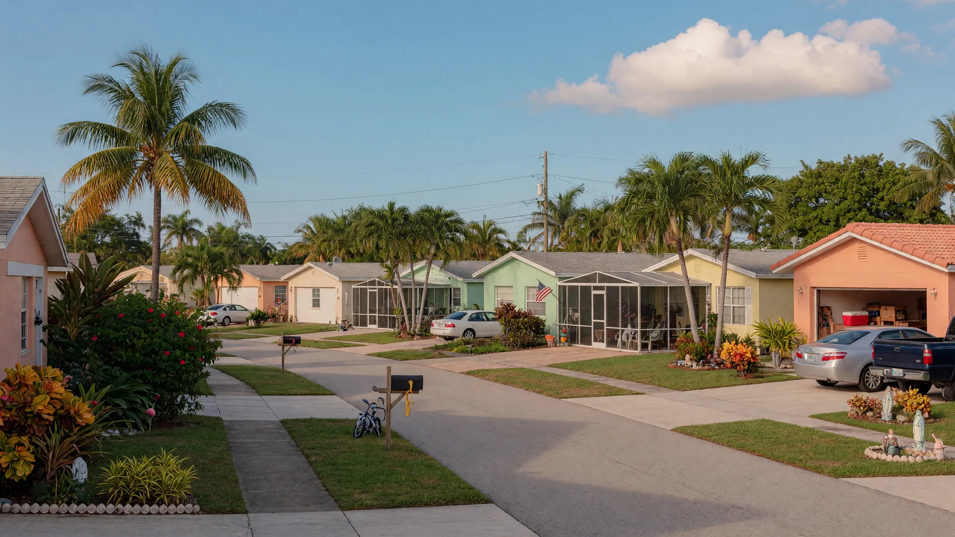 Quiet residential street in Boynton Beach with modest ranch homes, palm trees, and tropical landscaping
