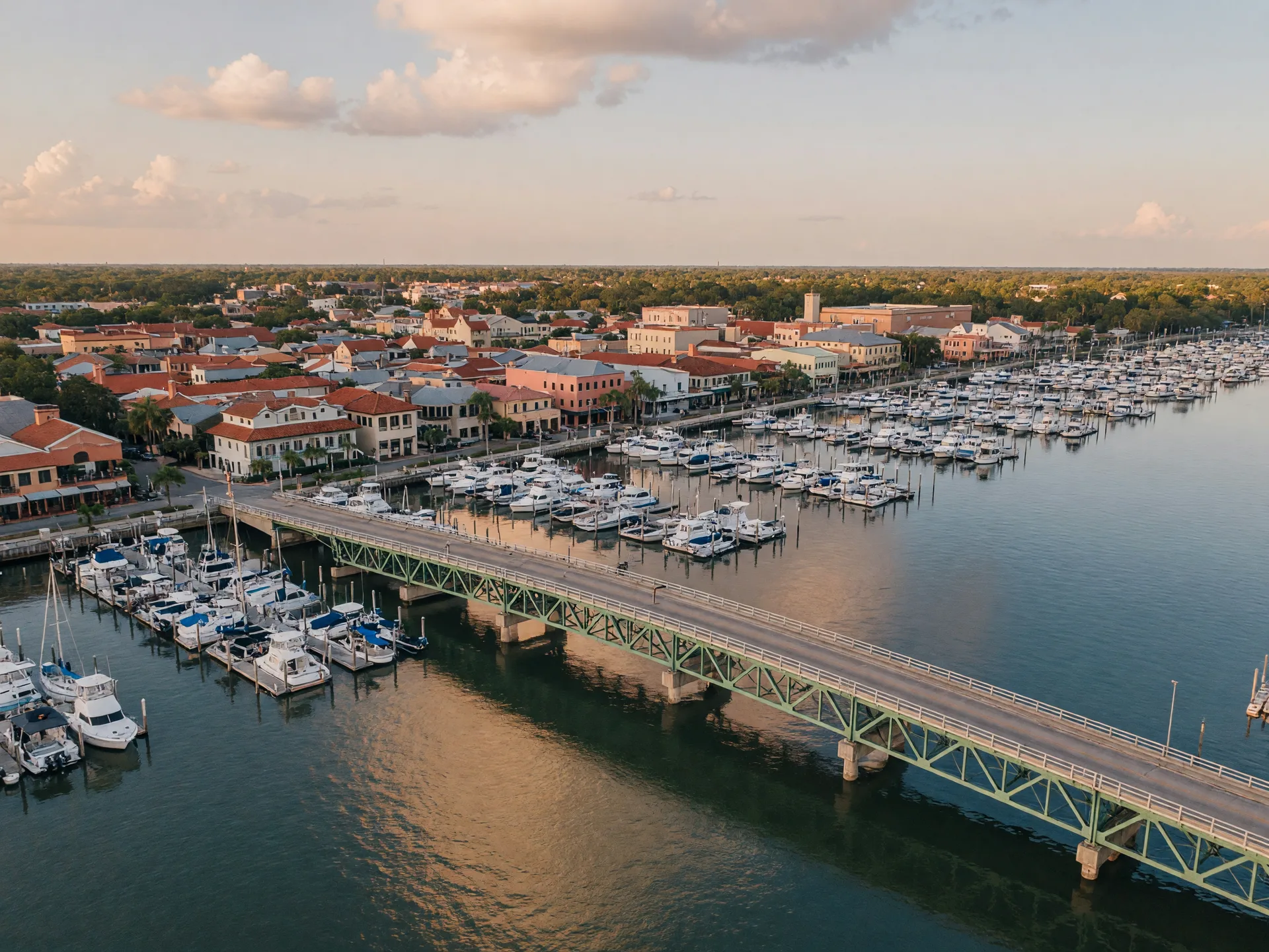 Aerial of the Green Bridge crossing the wide Manatee River at Palmetto, with a marina of white boats and the low-rise downtown along the north bank