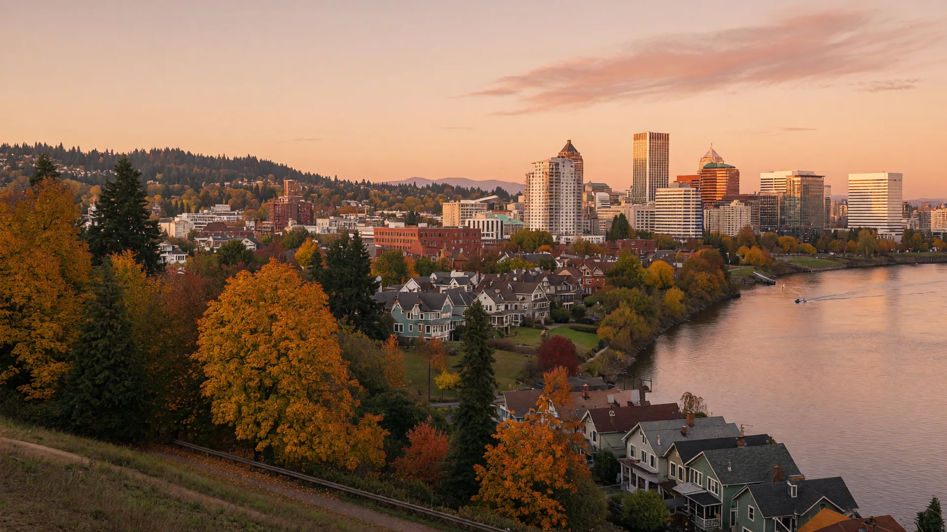 Portland Oregon skyline at golden hour in early autumn across the Willamette River with forested hills turning gold