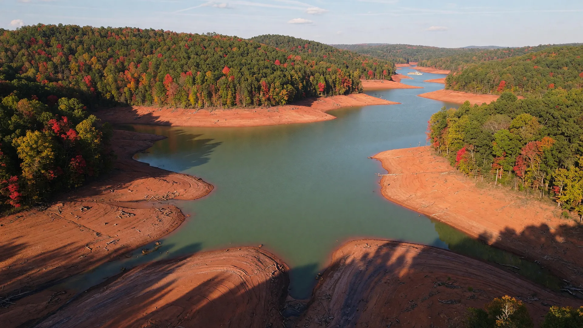 Aerial view of Lake Hartwell in autumn with broad red-clay banks exposed by the low water level and early fall color on the surrounding hills