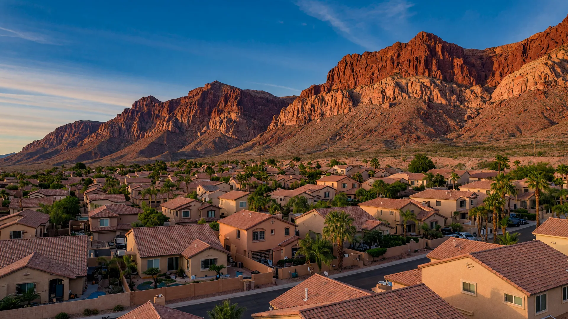 Red Rock escarpment rising behind two-story tile-roofed homes in far-west Summerlin at late afternoon