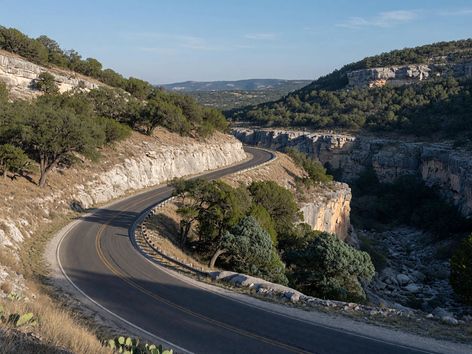 Empty curving ranch road of the Twisted Sisters climbing through rugged limestone hill country near Leakey in clear morning light
