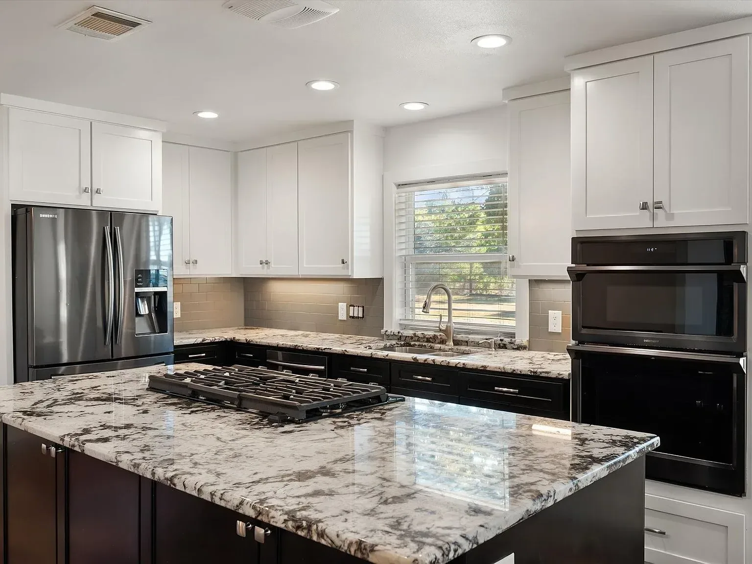 Renovated kitchen with granite counters and double wall ovens