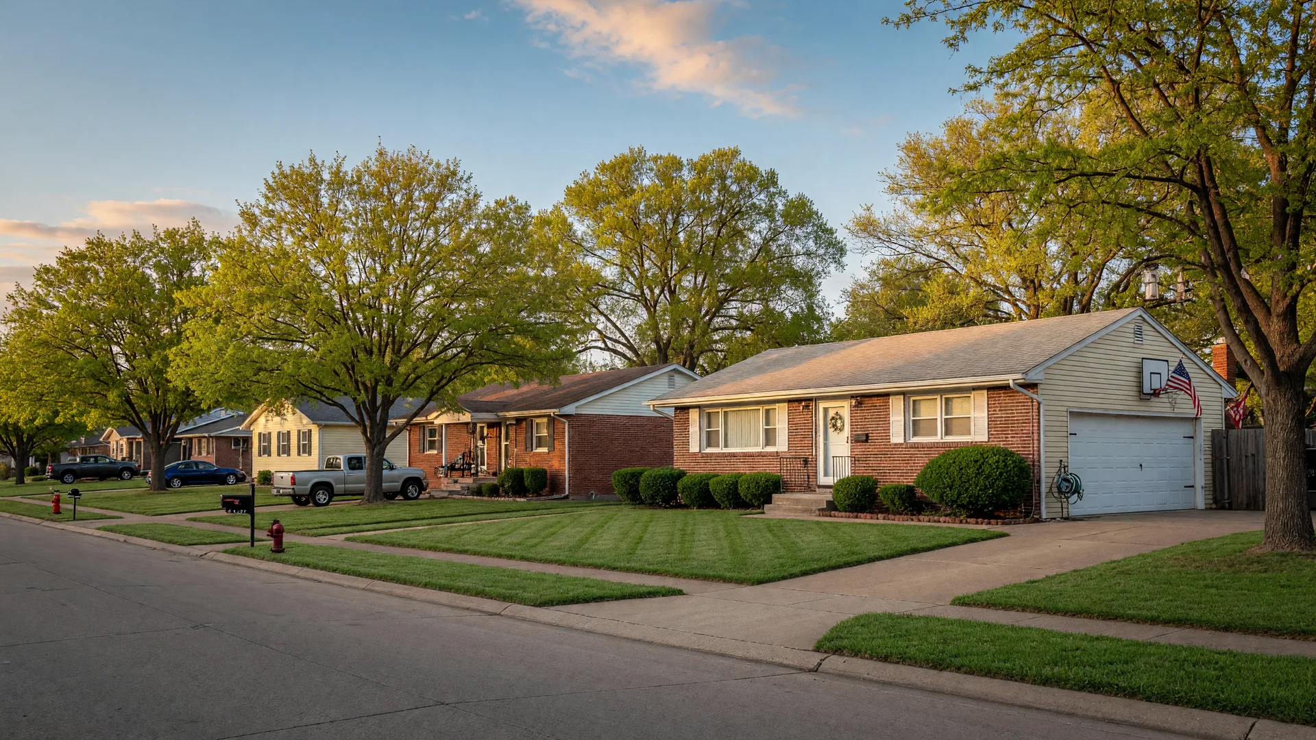 Tidy brick-and-siding suburban home in a small Oklahoma town with a neat front lawn and a two-car garage