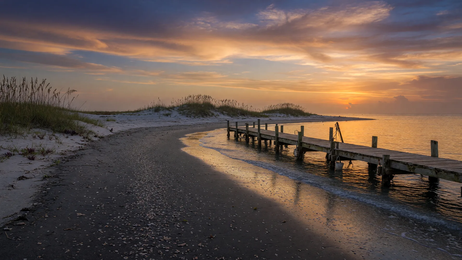 Quiet natural beach at sunset with a weathered fishing jetty on Casey Key