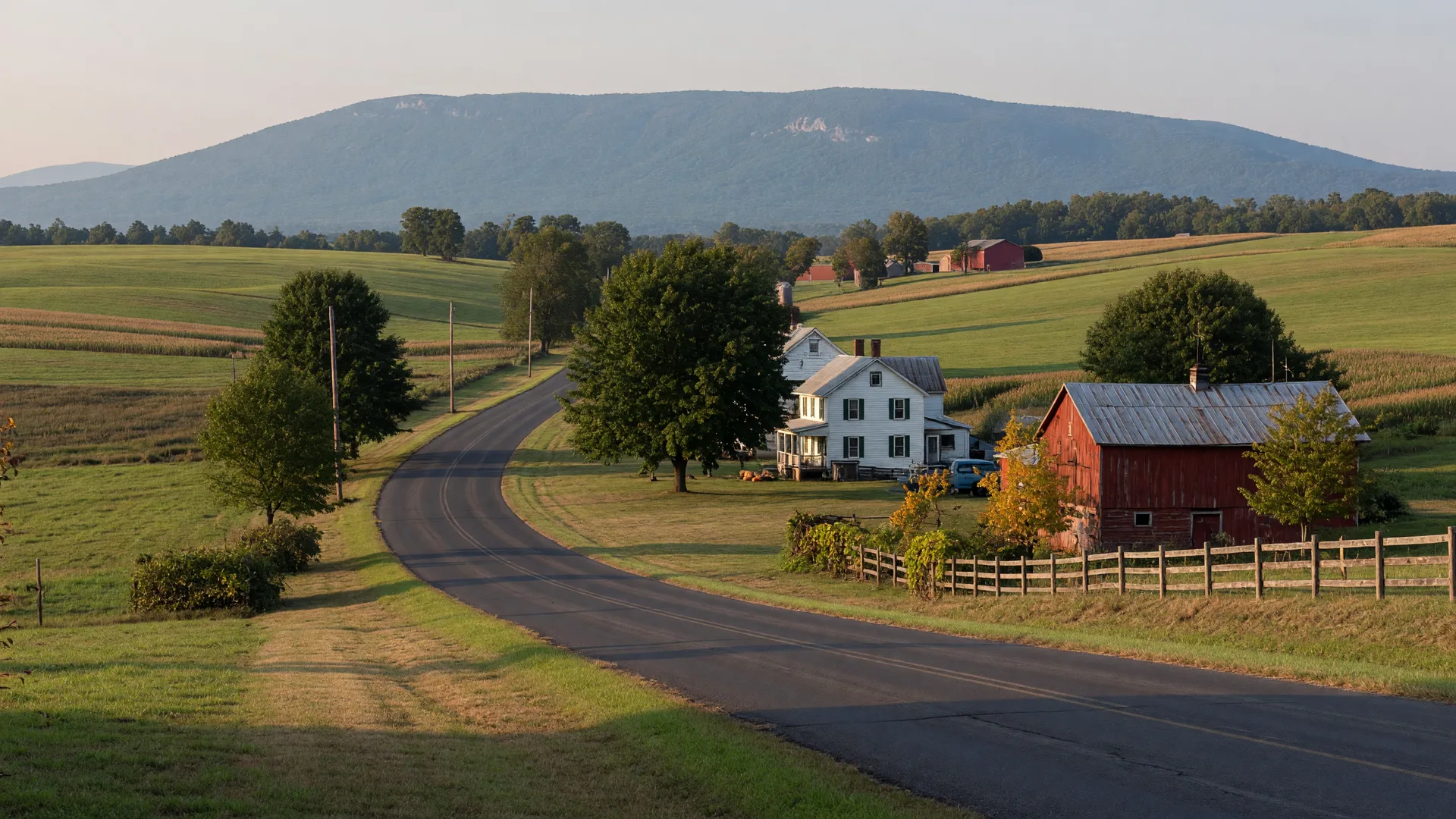 A winding rural Lehigh County road in early-autumn color with a red barn and the Blue Mountain ridge on the horizon