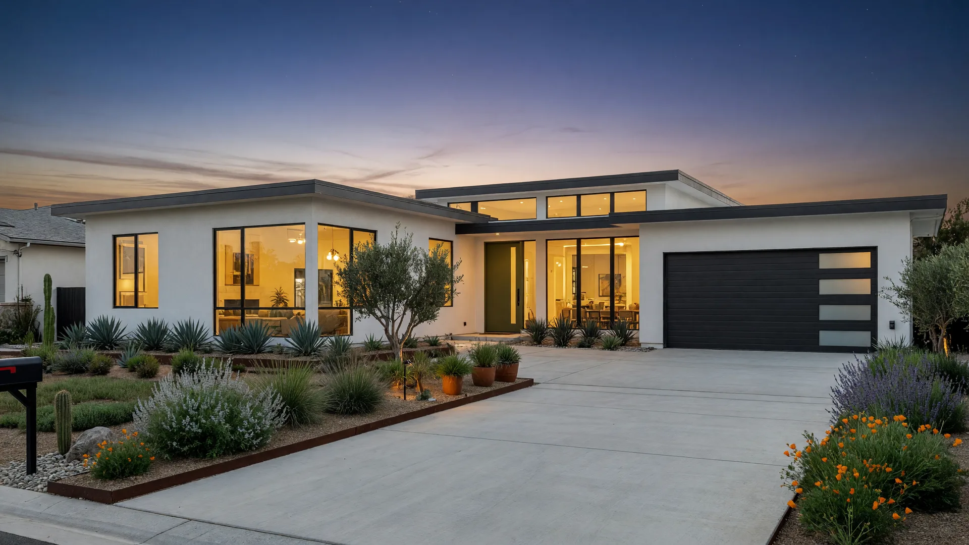 A contemporary Southern California suburban home at dusk with warm light glowing from its windows