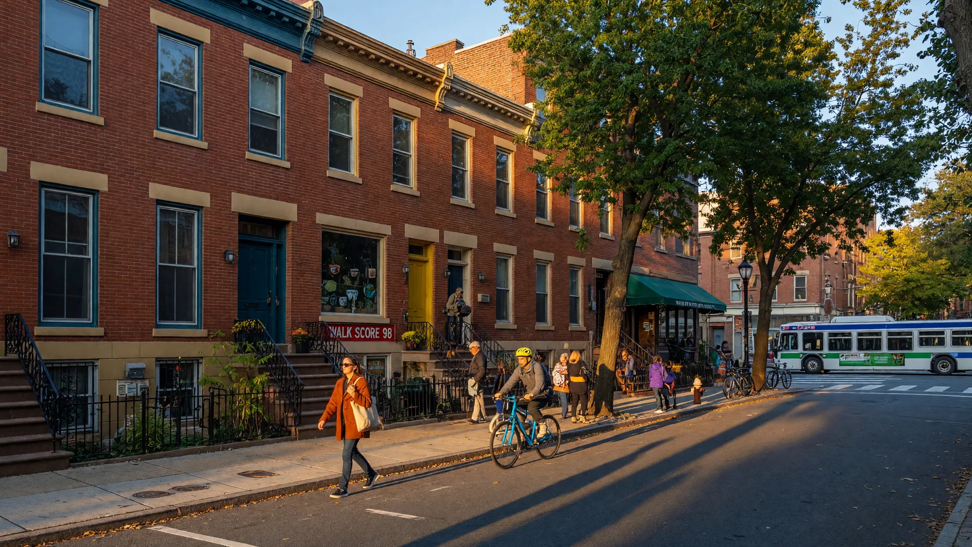 Tree-lined street in Washington Square West, Philadelphia with historic rowhomes, pedestrian activity, and daily street life