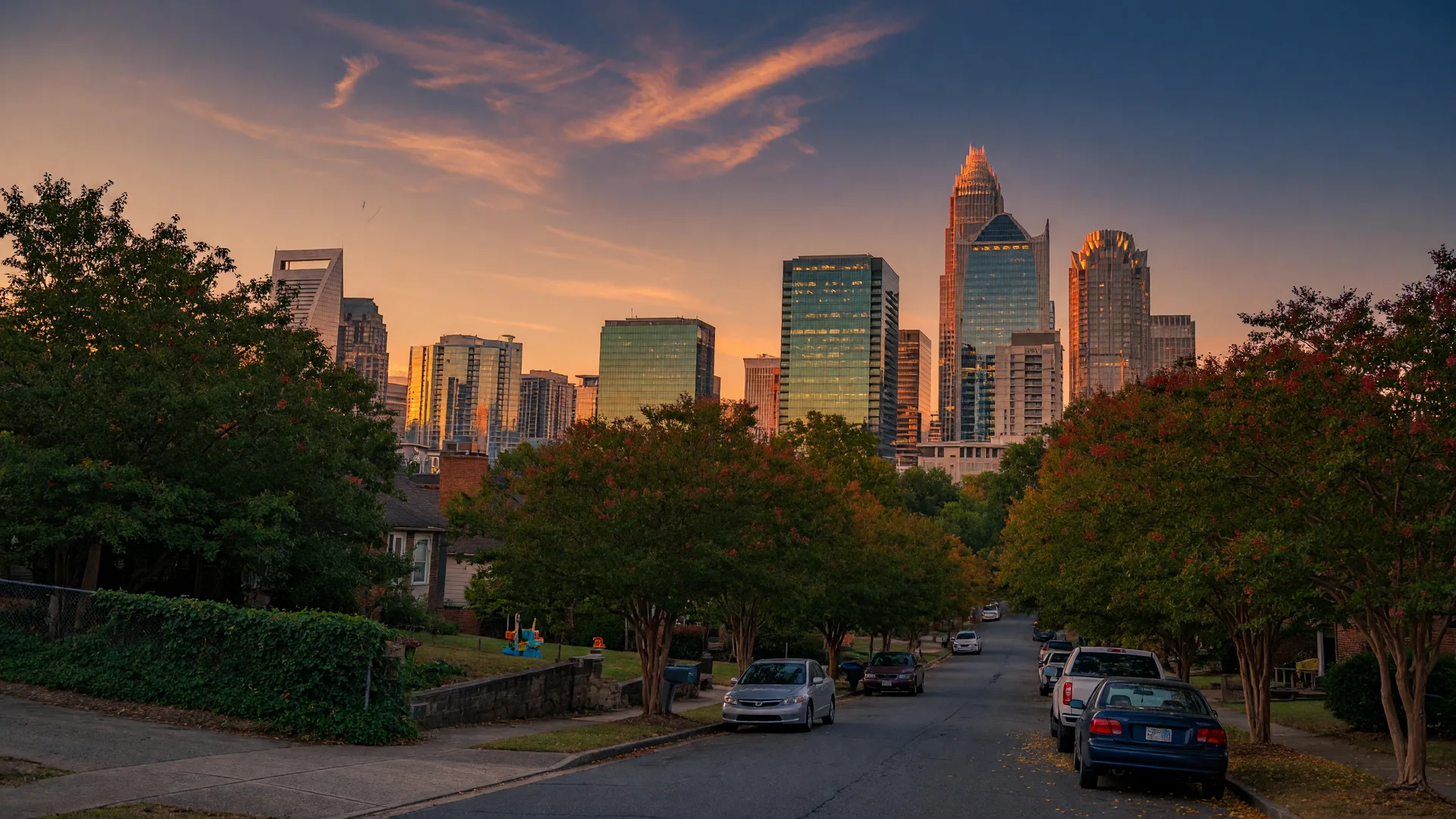 Uptown Charlotte NC skyline glowing at golden hour above a leafy residential street