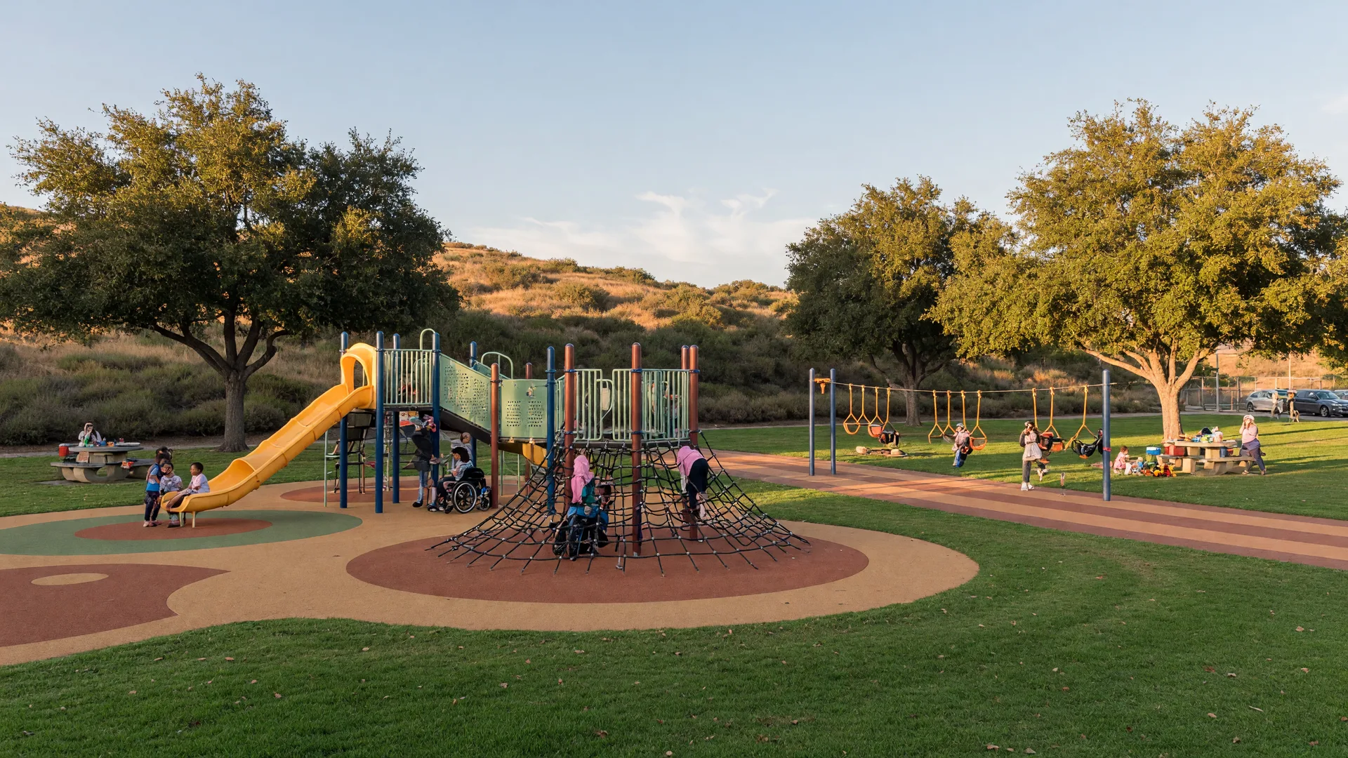 A sunny Valencia neighborhood park with an inclusive playground, green lawns, and rolling hills