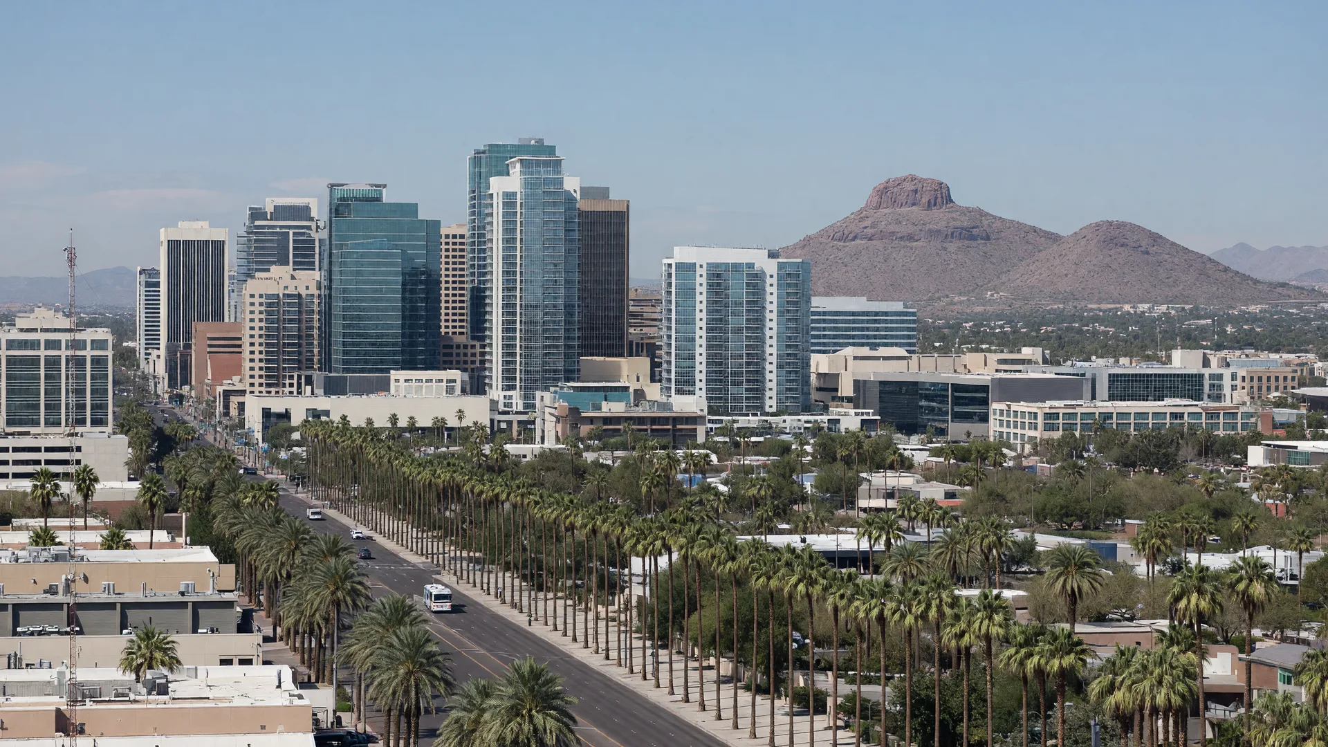 Downtown Phoenix skyline at dusk from a desert overlook with saguaro silhouettes