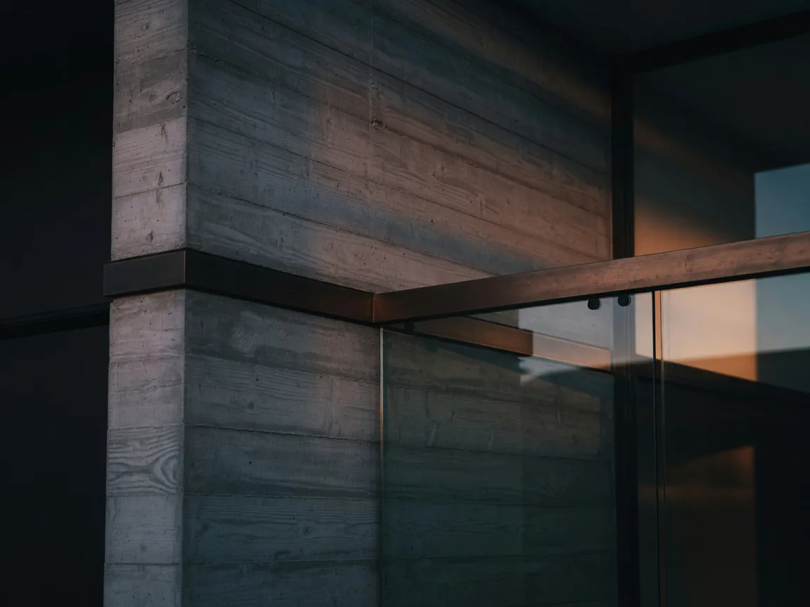 Architectural detail of a modern South Florida home: board-formed concrete meeting bronze trim and glass at dusk