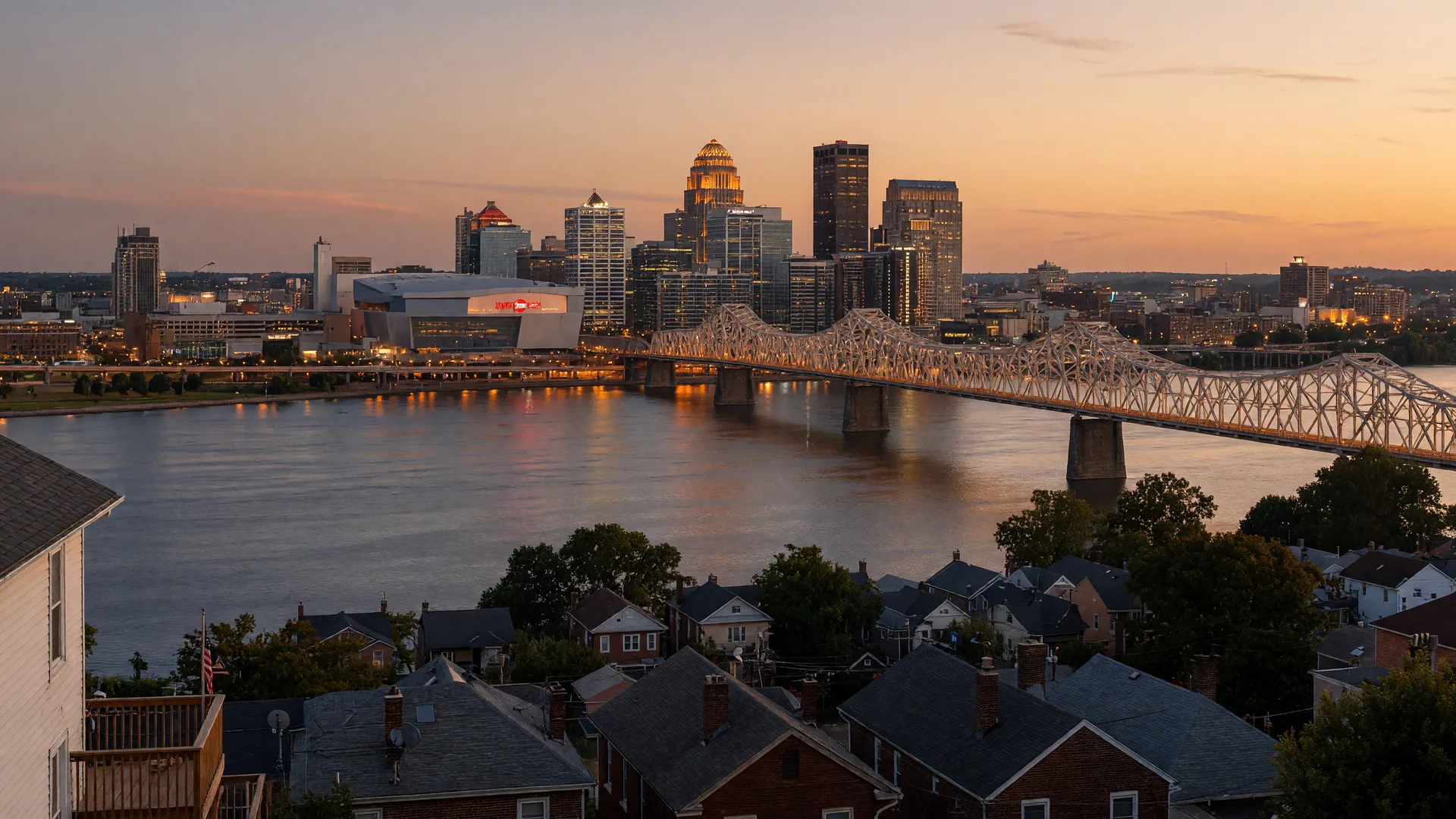 The Louisville skyline across the Ohio River at golden hour, with quiet residential neighborhoods in the foreground