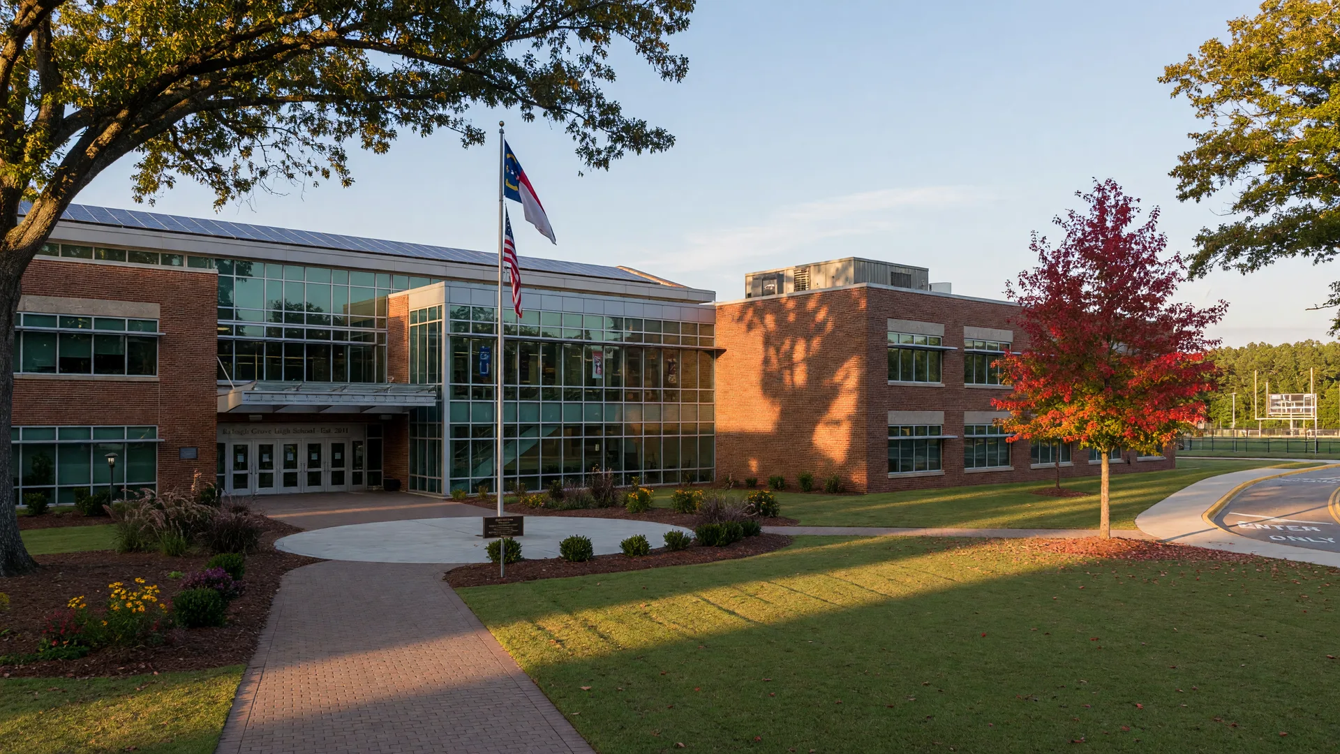 Modern brick and glass public high school campus in a Raleigh Triangle suburb on a late-summer morning