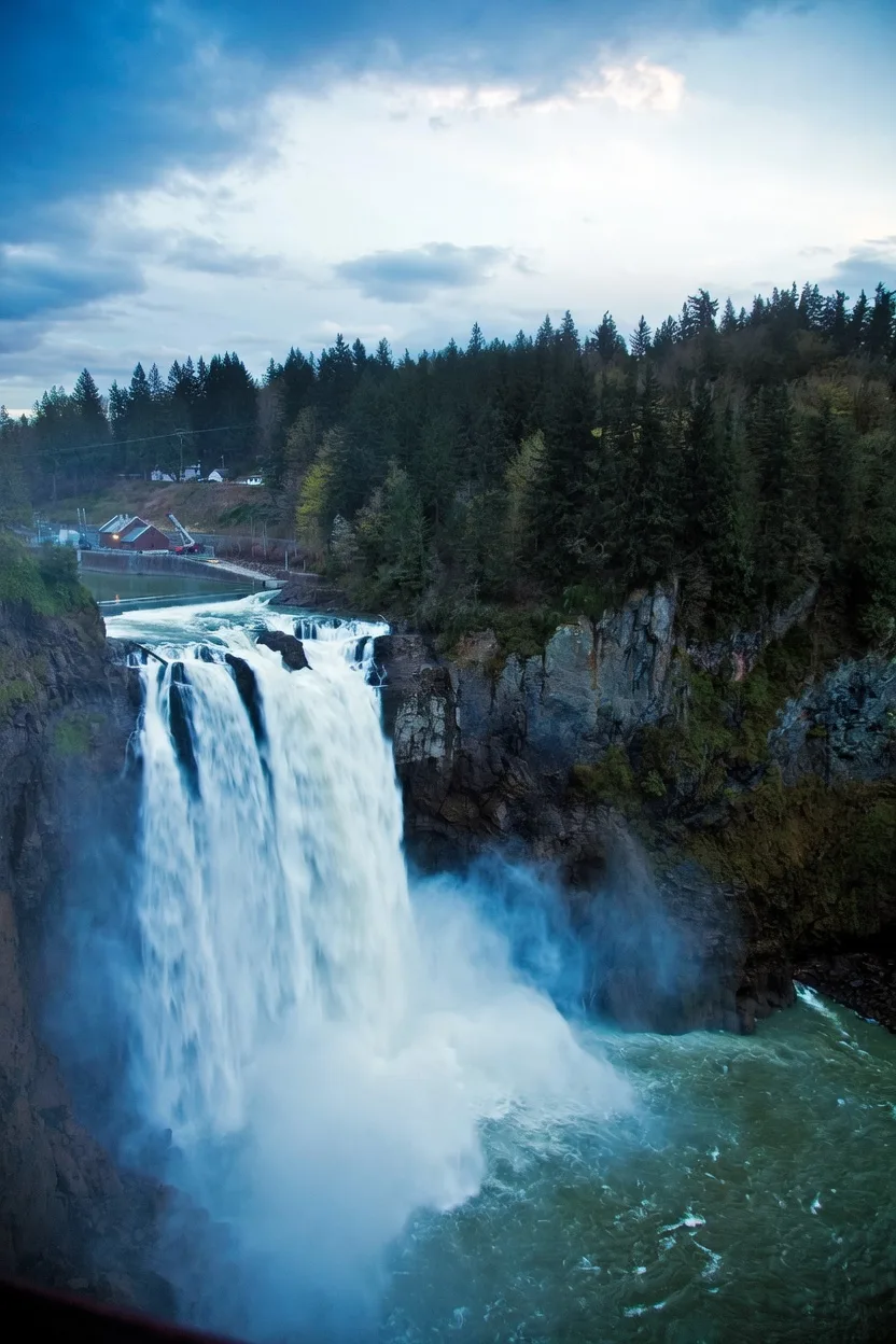 Snoqualmie Falls cascading into a forested basin under a cloudy sky