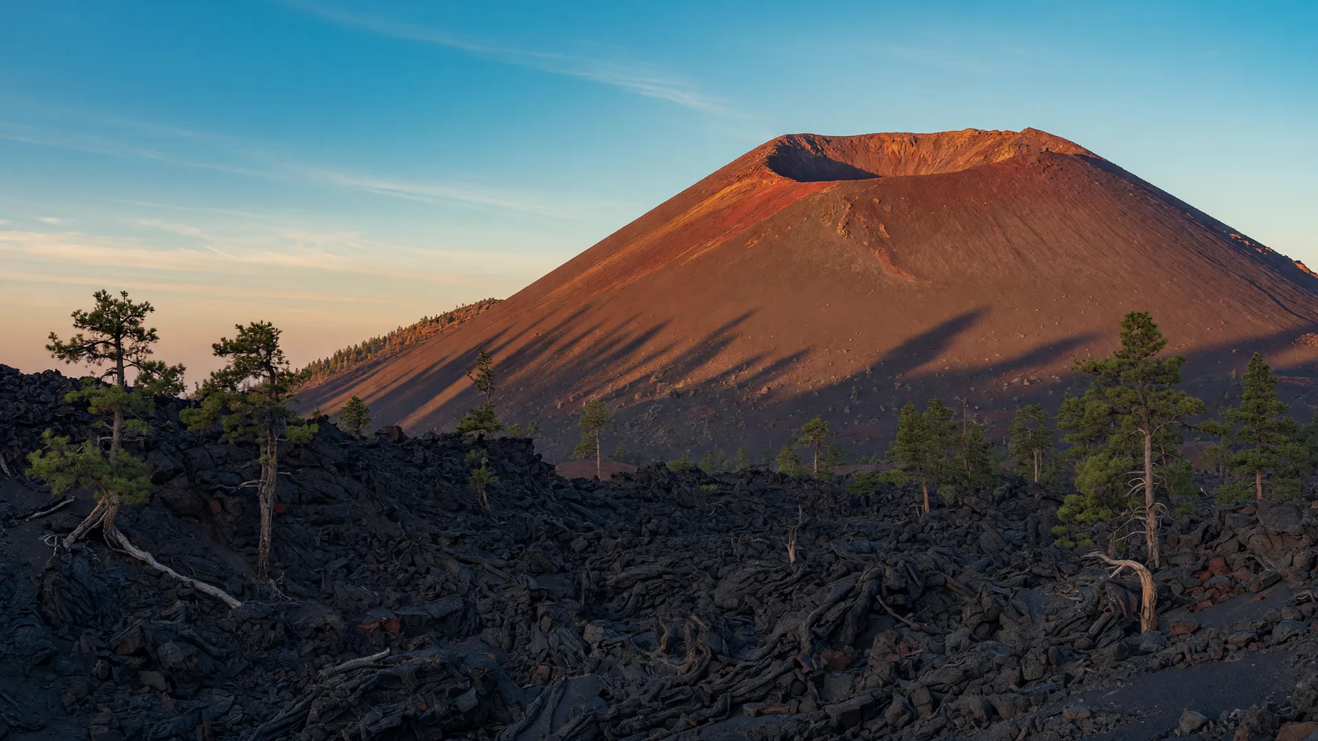 Sunset Crater volcano in northern Arizona with its reddish cinder cone above dark basalt lava fields