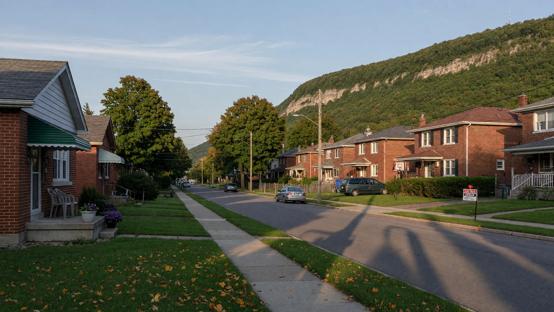 Quiet Hamilton Mountain residential street in early September with brick bungalows, mature trees, and soft late-afternoon light