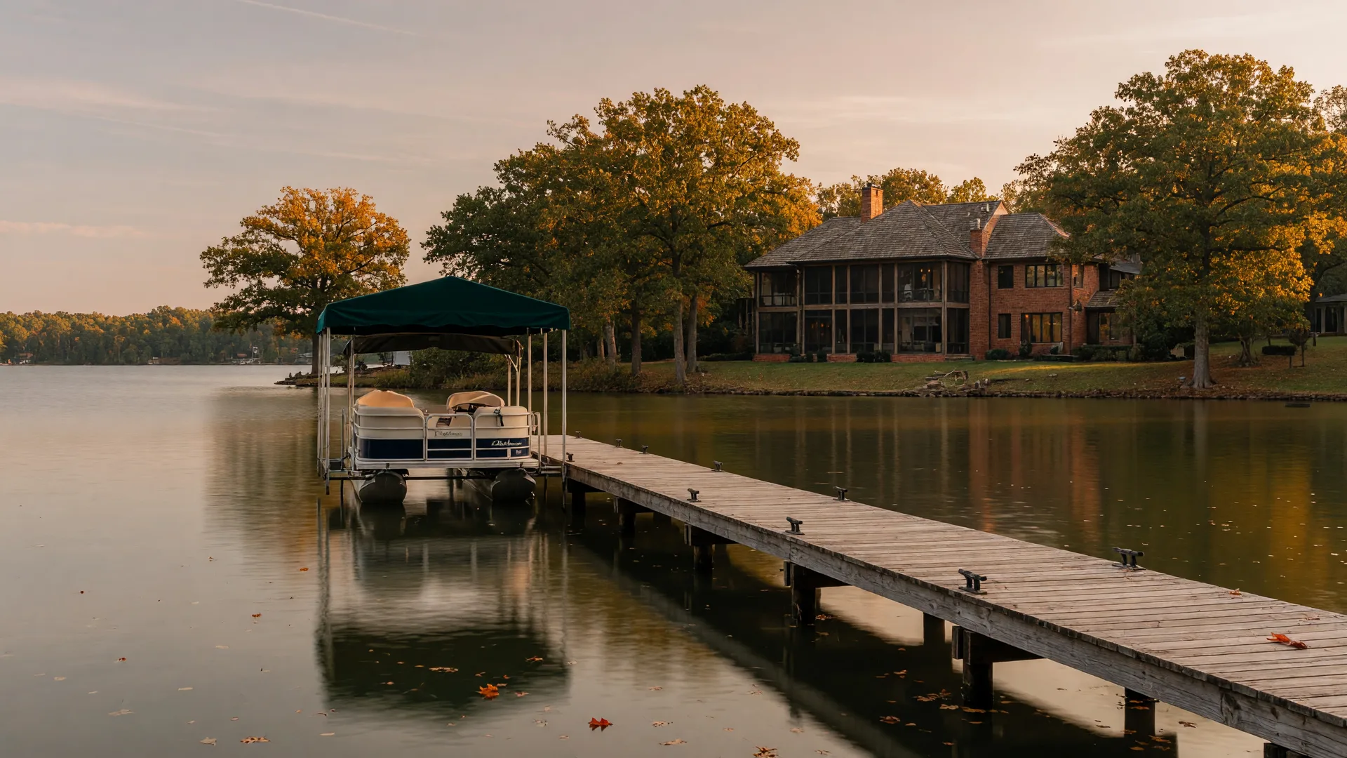 A Lake Norman waterfront dock and boathouse in early autumn, with amber shoreline trees, a covered boat lift, and calm golden water at the boat slip