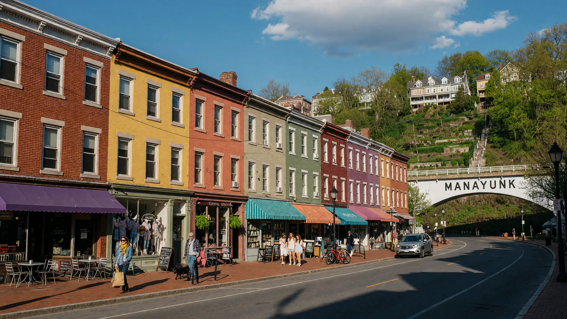 Manayunk Main Street with colorful brick buildings and steep hillside in the background