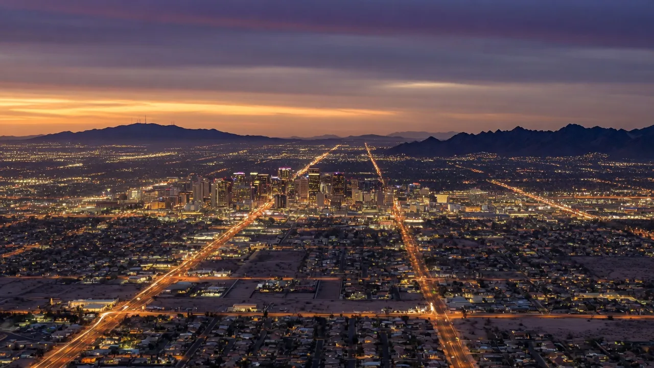 Aerial view of the Phoenix metro area at dusk with the city lights spreading across the desert basin