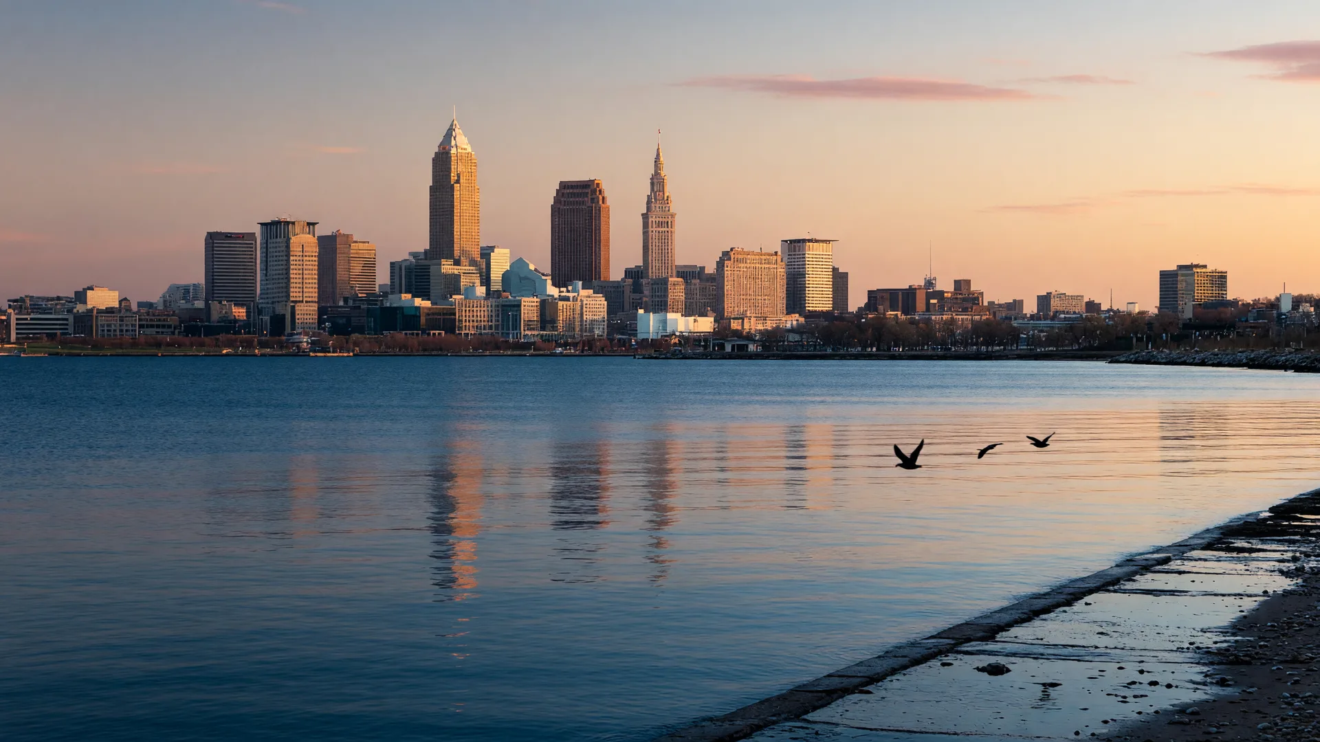 Sunrise view of the Cleveland Ohio skyline from the Lake Erie waterfront with calm dawn light over the water