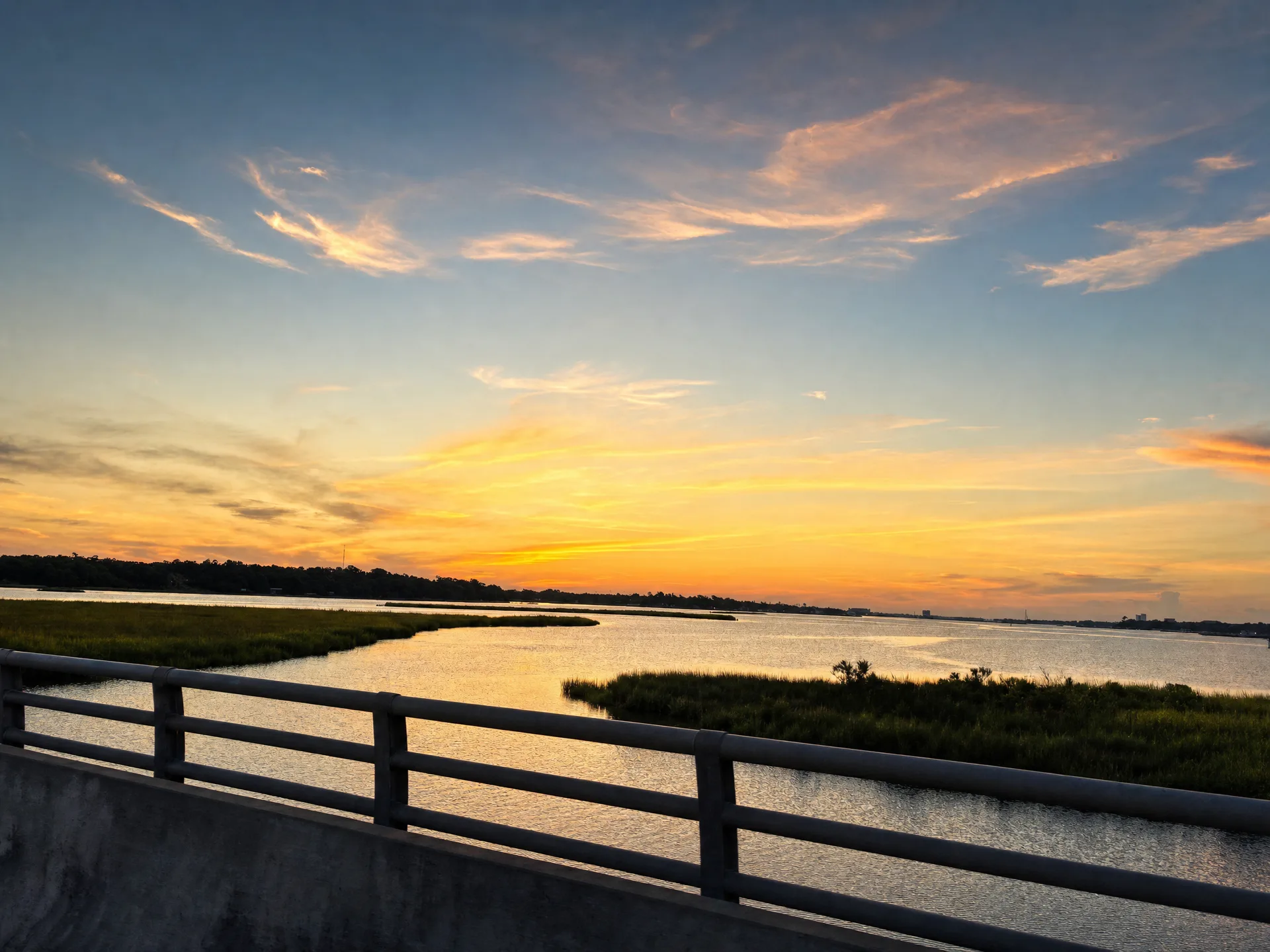 A scenic sunset over a waterway with marshland visible in the distance on the Mississippi Gulf Coast