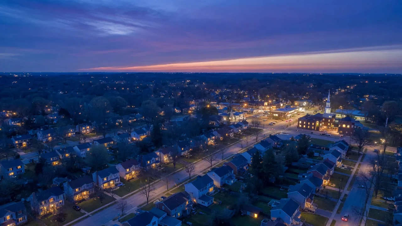 Aerial view of suburban neighborhood at blue hour with warm house lights