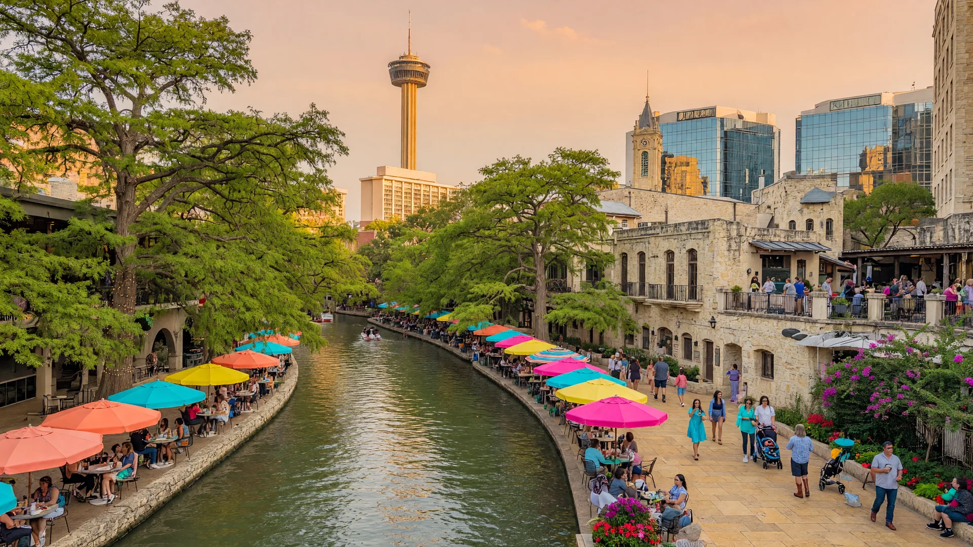 San Antonio River Walk — cypress trees, colorful umbrellas over outdoor cafes, and the Tower of the Americas under warm afternoon light