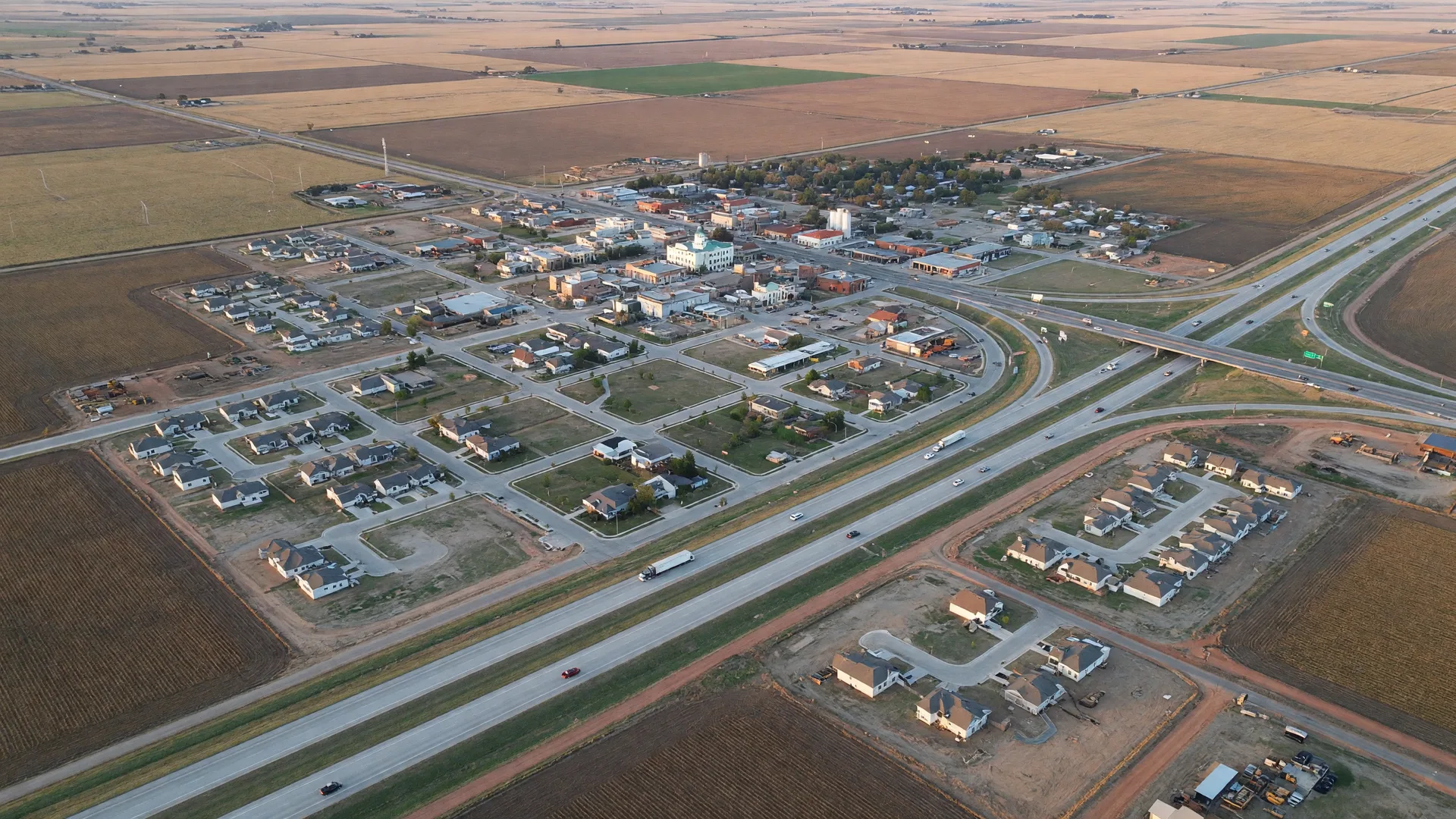 An aerial view of a growing small Texas city on flat farmland with a neat street grid, a compact downtown, and new subdivisions at the edges