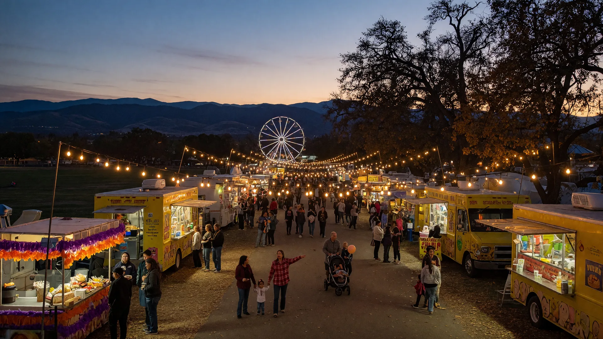 A lively Central Valley autumn community evening in Merced County, warm string lights strung over a fairgrounds walkway with food trucks and vendor booths, families strolling, and the Sierra Nevada foothills silhouetted against a deep blue dusk sky