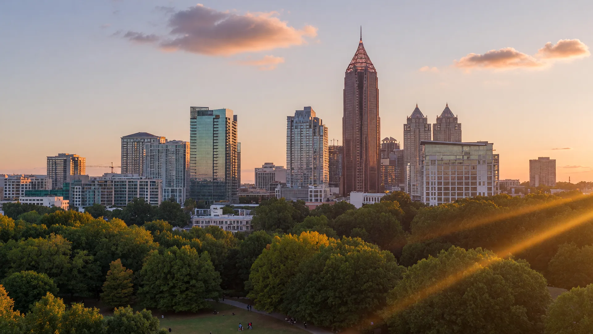 The Midtown Atlanta skyline rising above the green canopy of Piedmont Park in golden light
