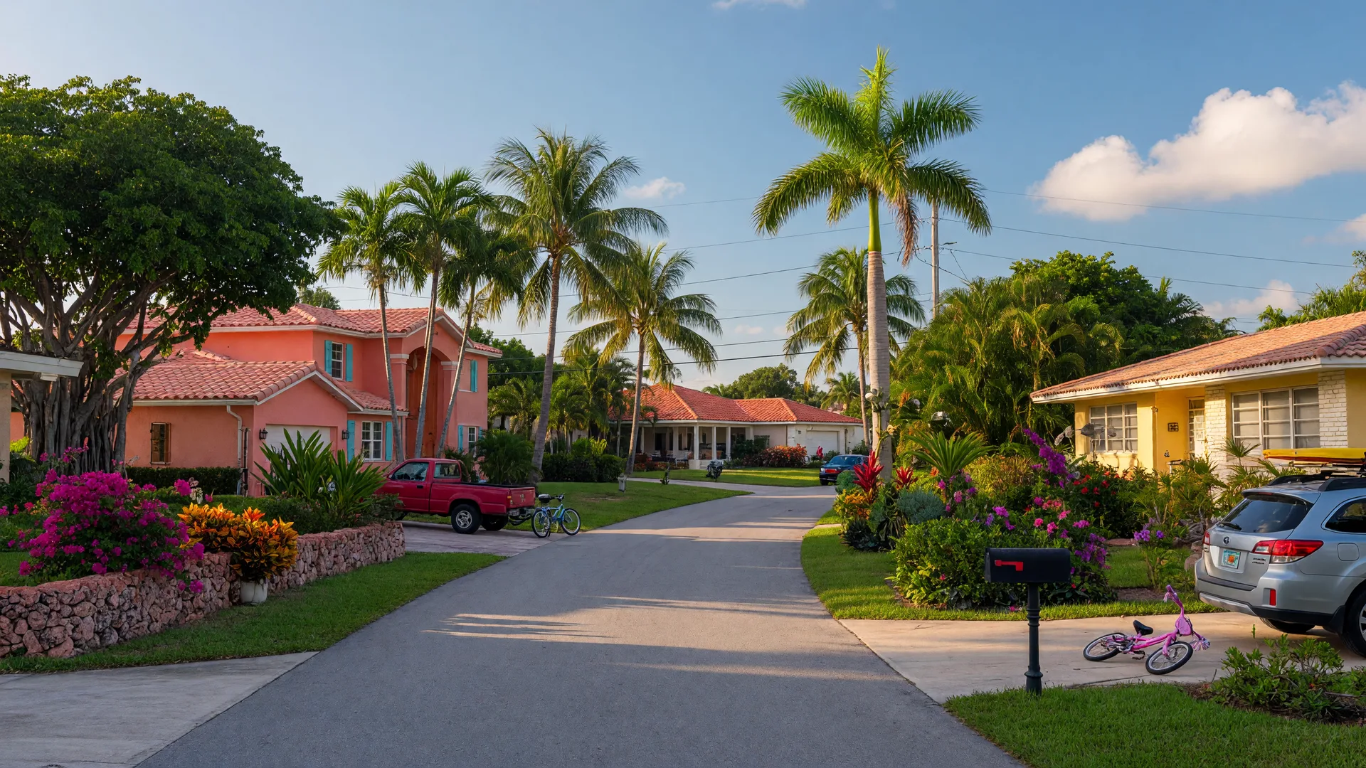 Tree-lined residential street in East Delray Beach, Florida with Mediterranean and ranch homes under a bright blue sky