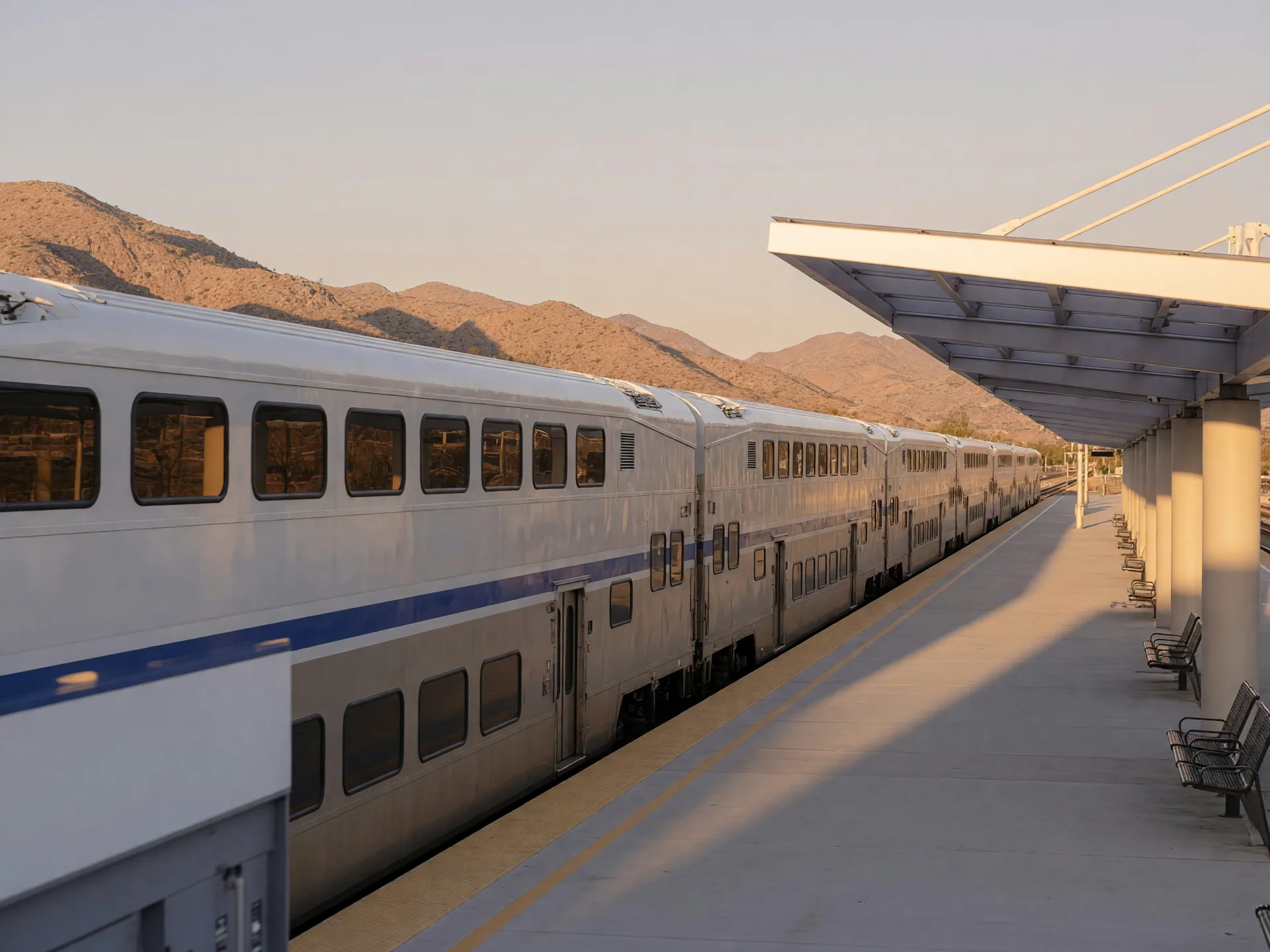 Metrolink commuter train at a Southern California station platform with desert mountains behind