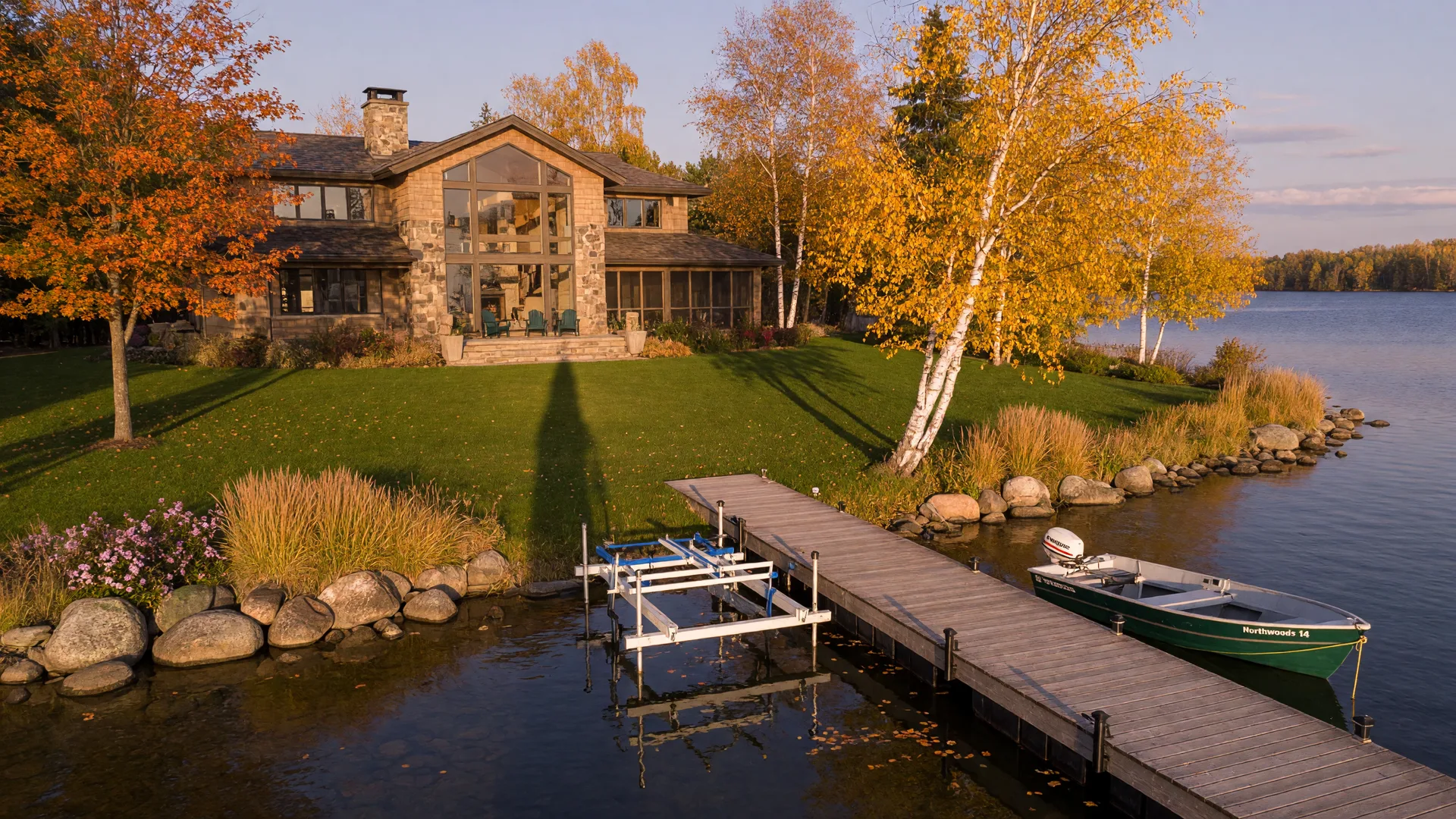 Upscale Minnesota lake home on a waterfront lot in autumn with a long wooden dock and boat lift on calm water