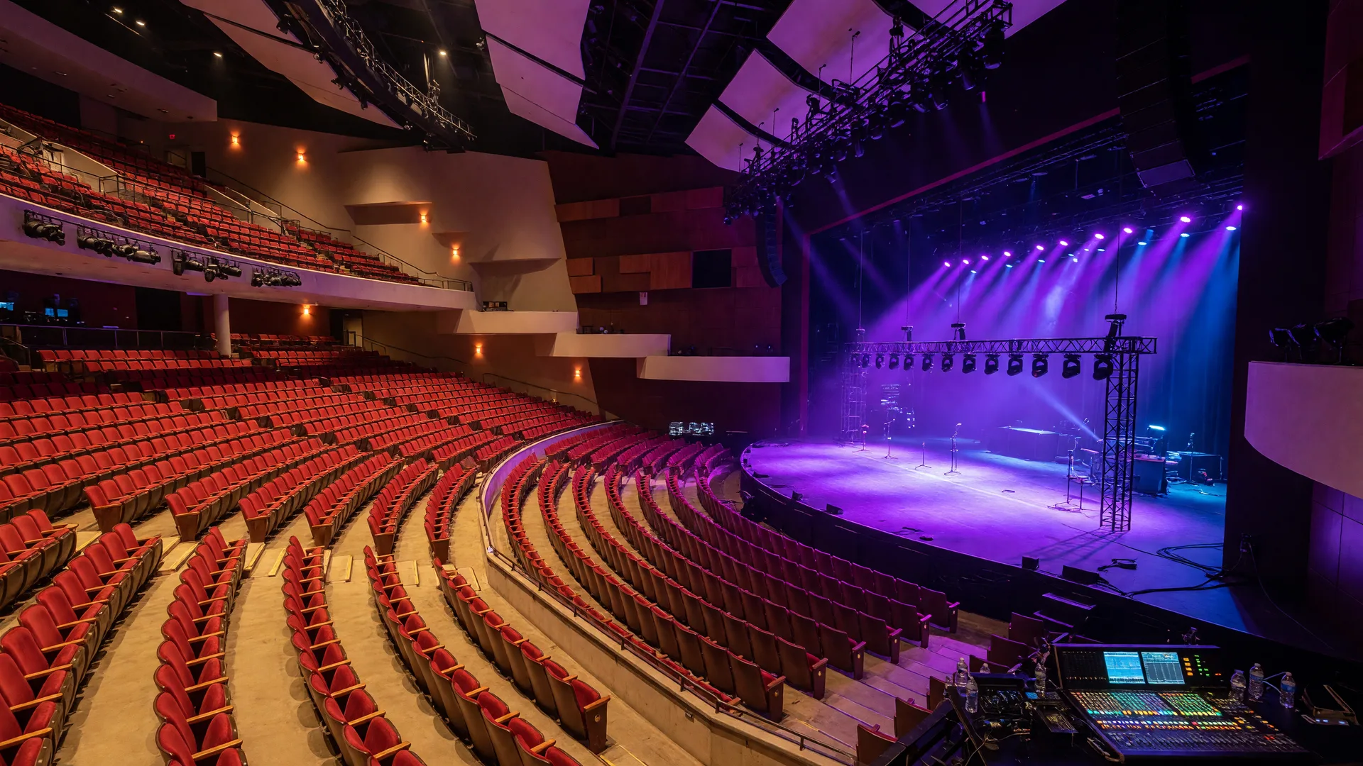 The Choctaw Grand Theater interior with purple and blue stage lighting illuminating a concert-ready stage and red velvet arena seating in Durant, Oklahoma
