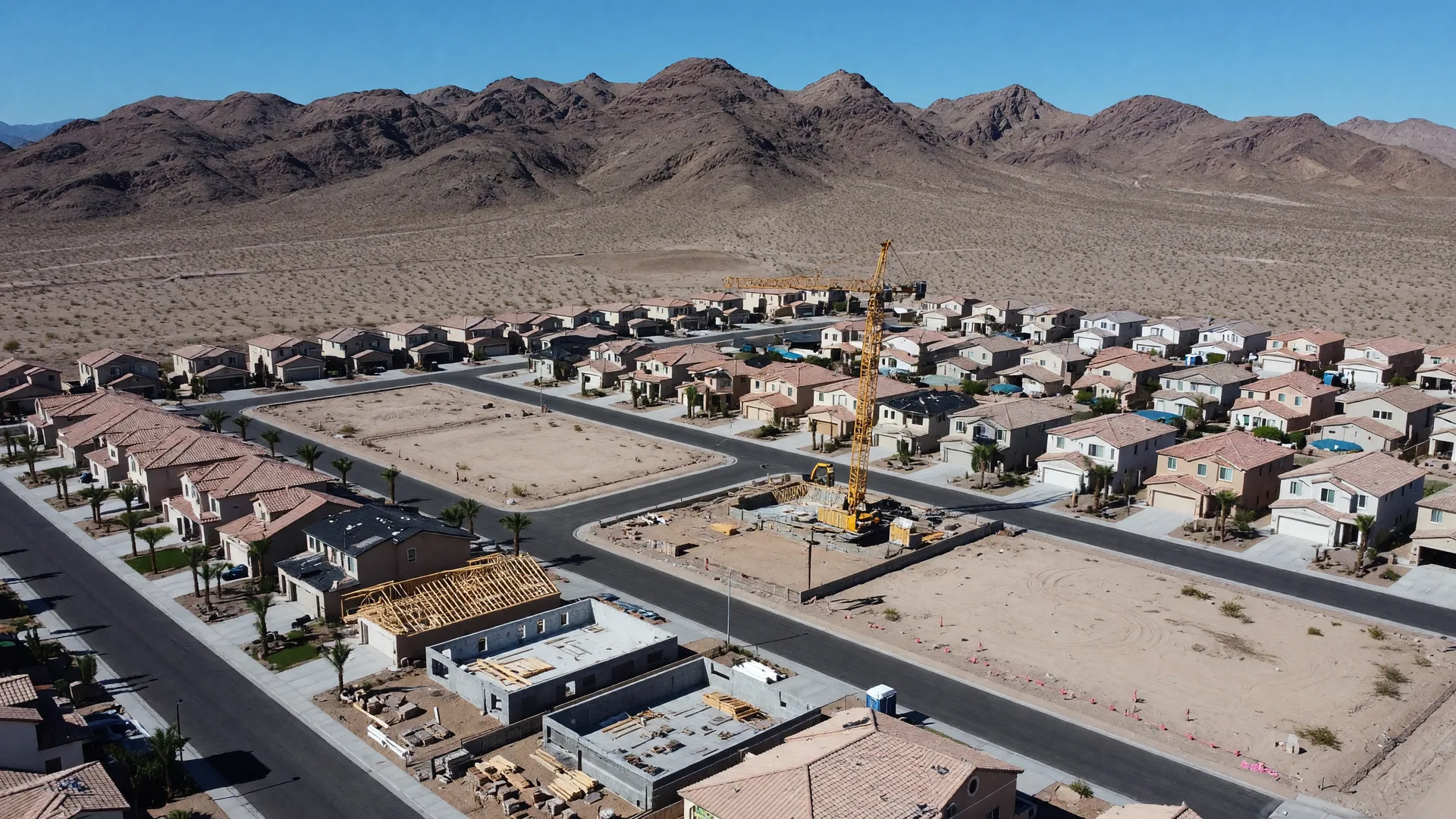 Aerial view of Las Vegas suburban neighborhood with homes under construction and desert mountains