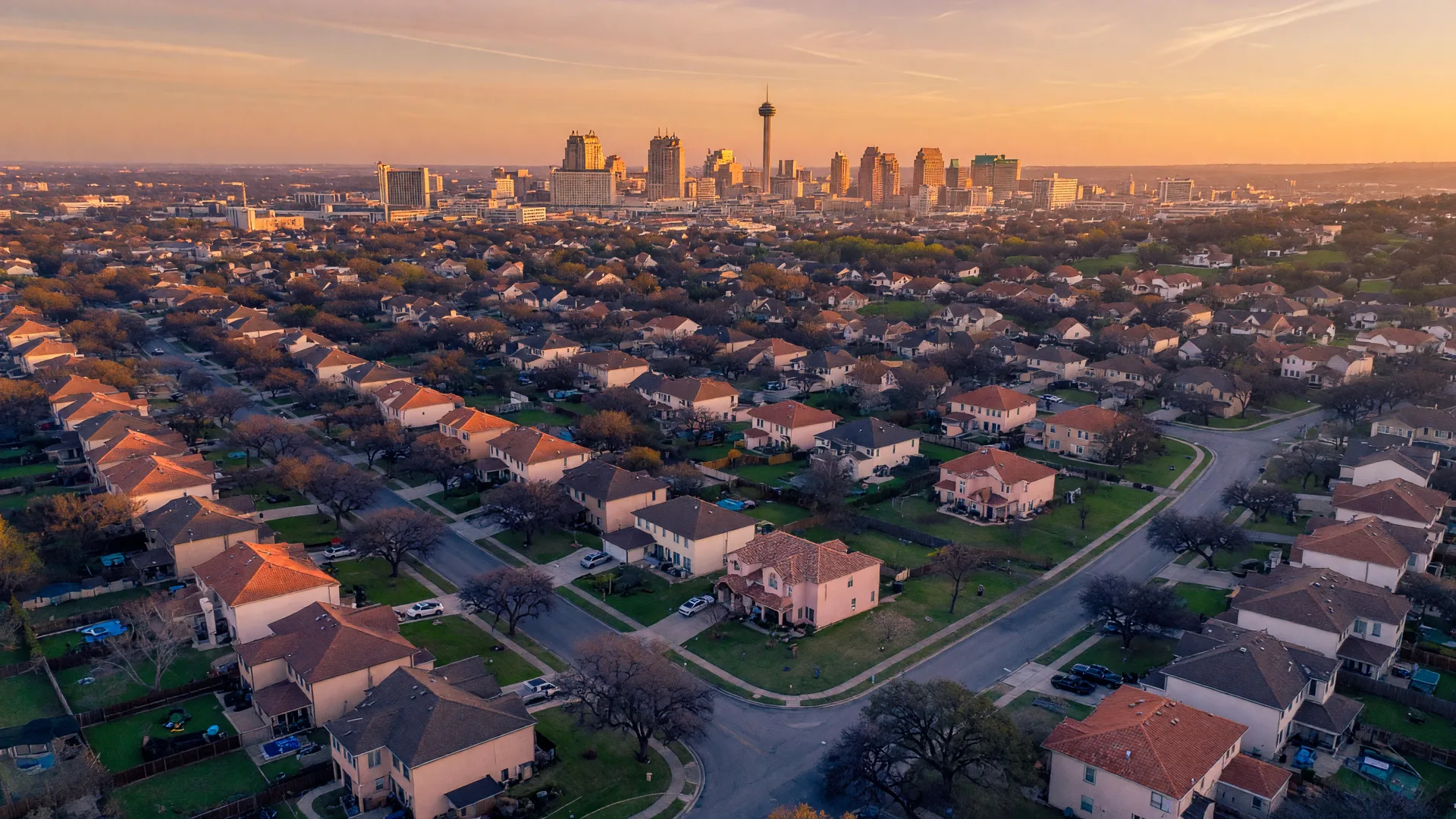 Aerial view of San Antonio neighborhoods at golden hour with the downtown skyline on the horizon