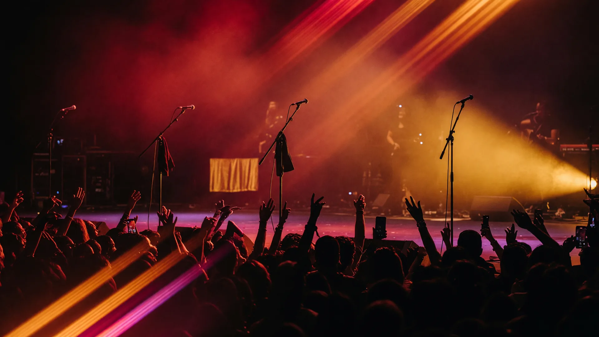 A live R&B concert stage in deep red and gold light with microphone stands and a silhouetted arena crowd