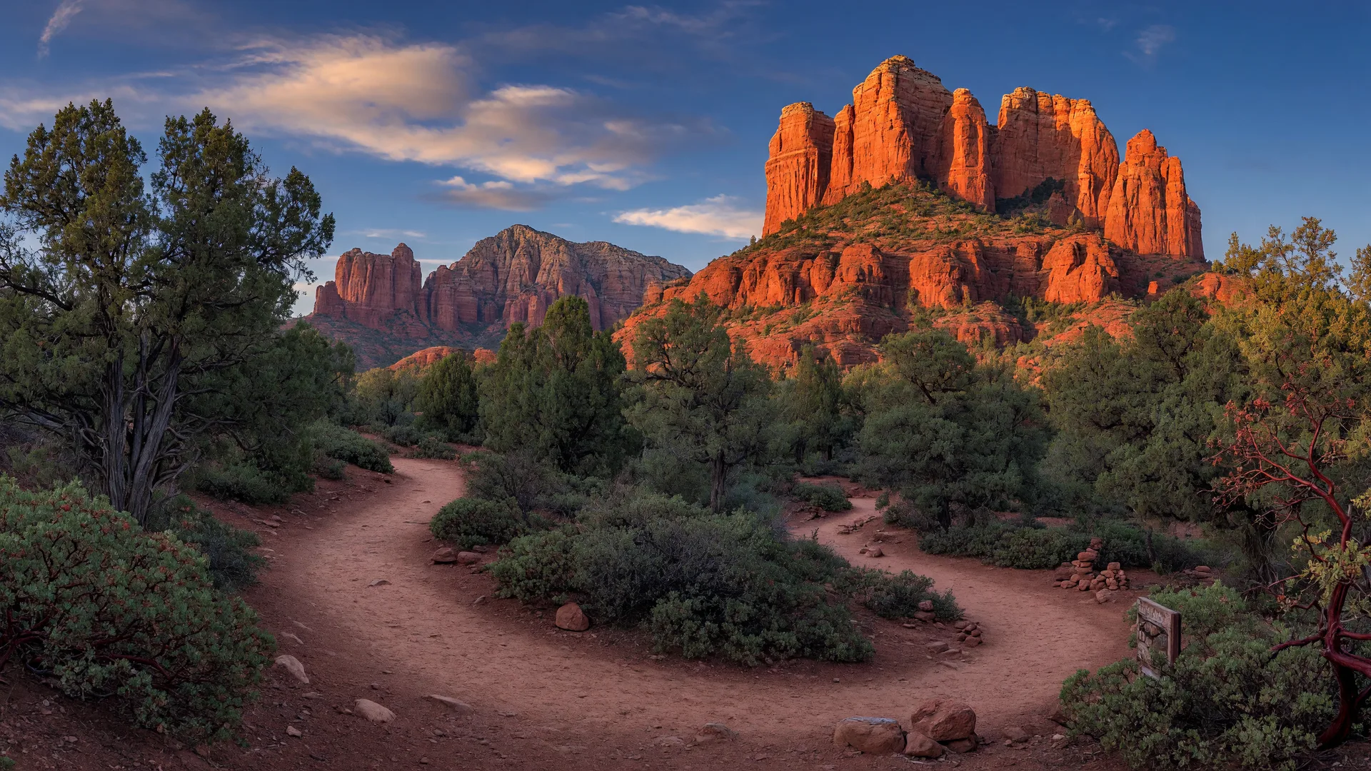 A desert hiking trail near Sedona winding toward Cathedral Rock glowing in golden evening light
