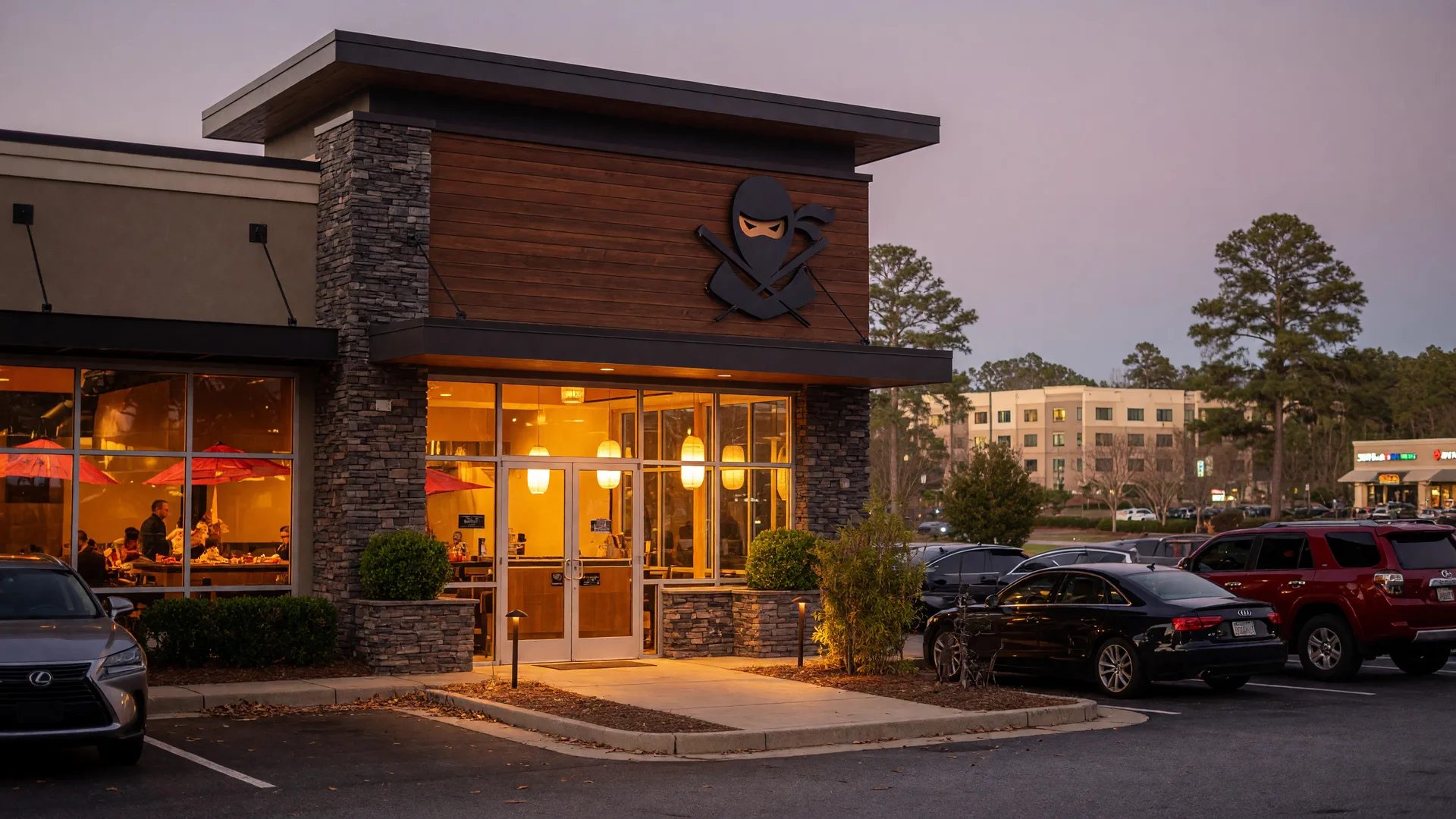 Exterior of an upscale casual Japanese hibachi steakhouse and sushi restaurant in Braselton Georgia glowing warmly at dusk