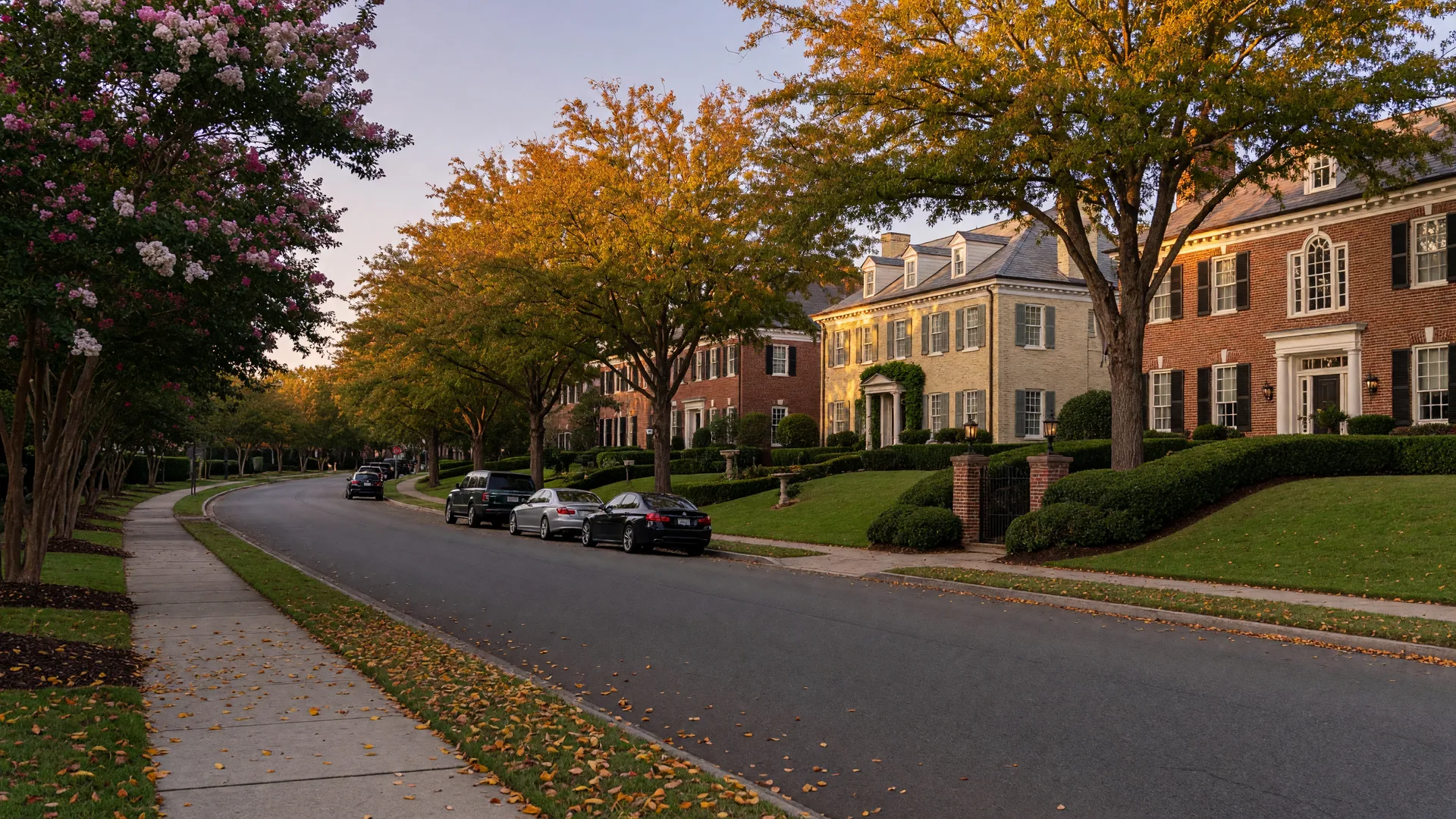 Tree-lined residential street in the Foxcroft neighborhood of Charlotte NC with grand brick estate homes under mature oaks at golden hour