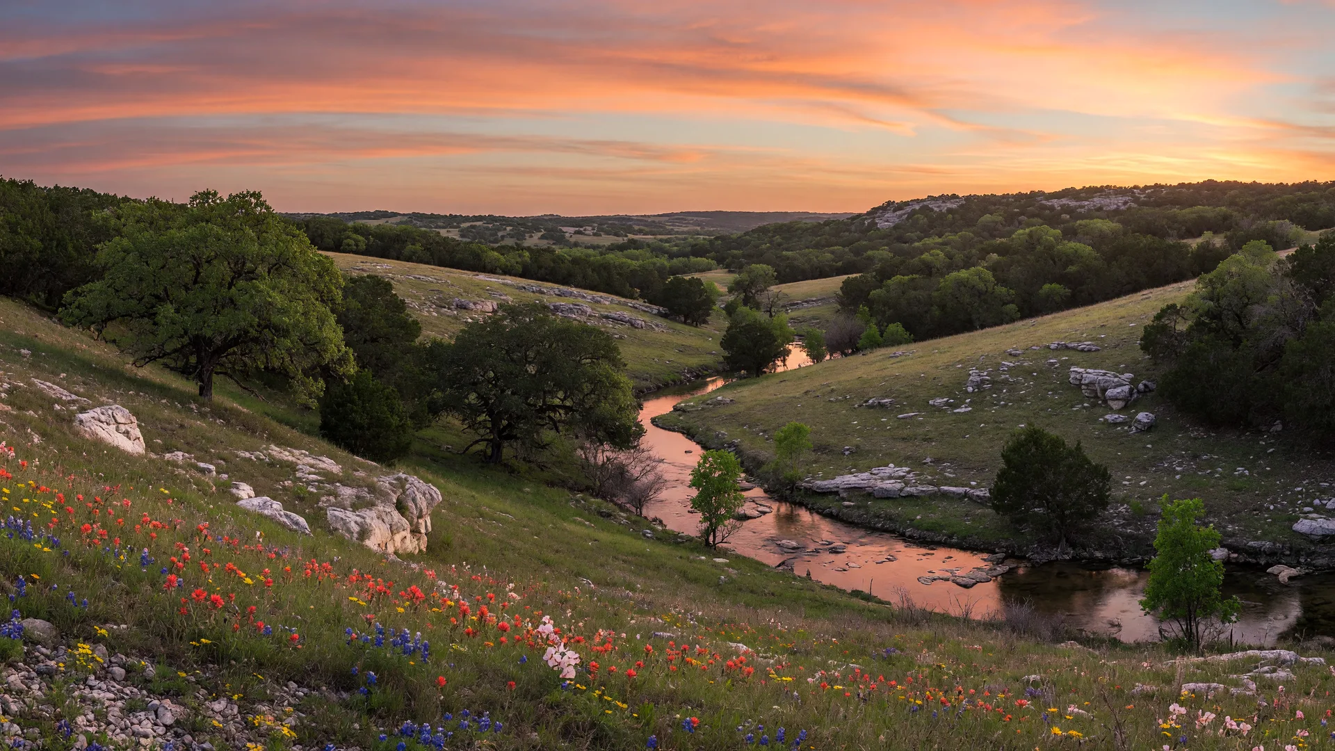 Rolling Texas Hill Country hills near Boerne with limestone outcrops and a winding creek at sunset